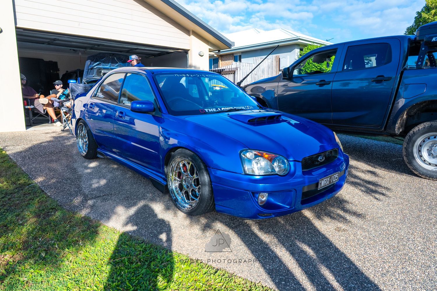 Five bright blue Subaru Impreza WRX cars parked in a row showing the evolution of the sporty sedan model.