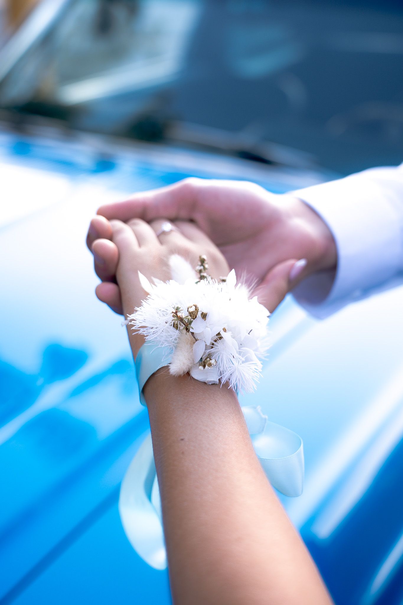 Delicate white dandelion seeds rest gently on a person's hand against a soft blue background.