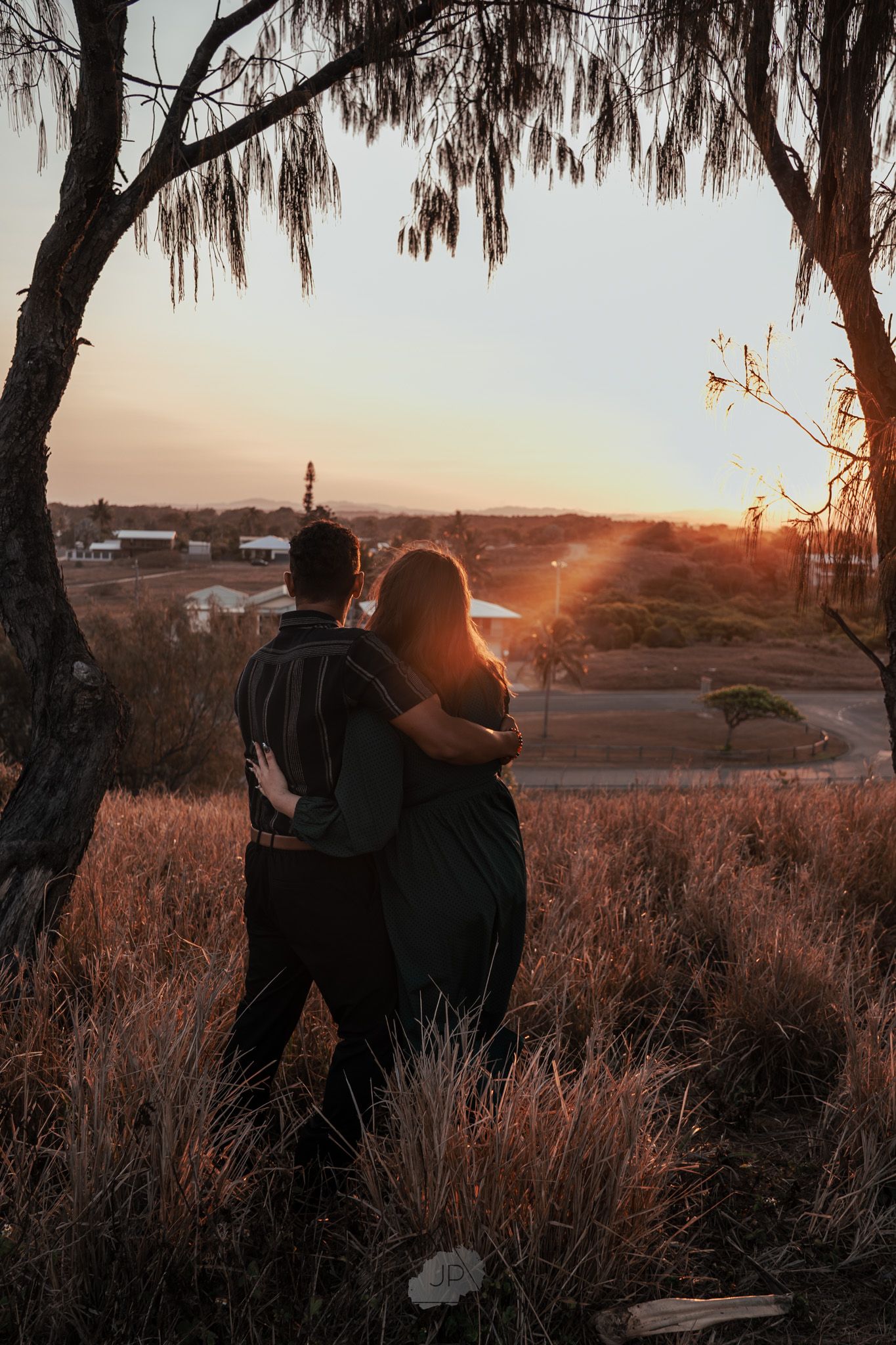 Silhouettes of two people walking under palm trees during a golden sunset.