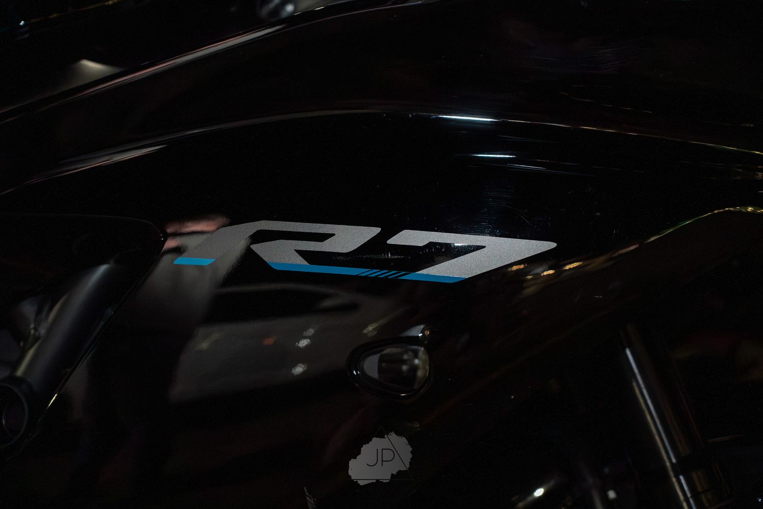 A close-up detail shot of a black Yamaha R7 motorcycle showing partial side fairing and branding.
