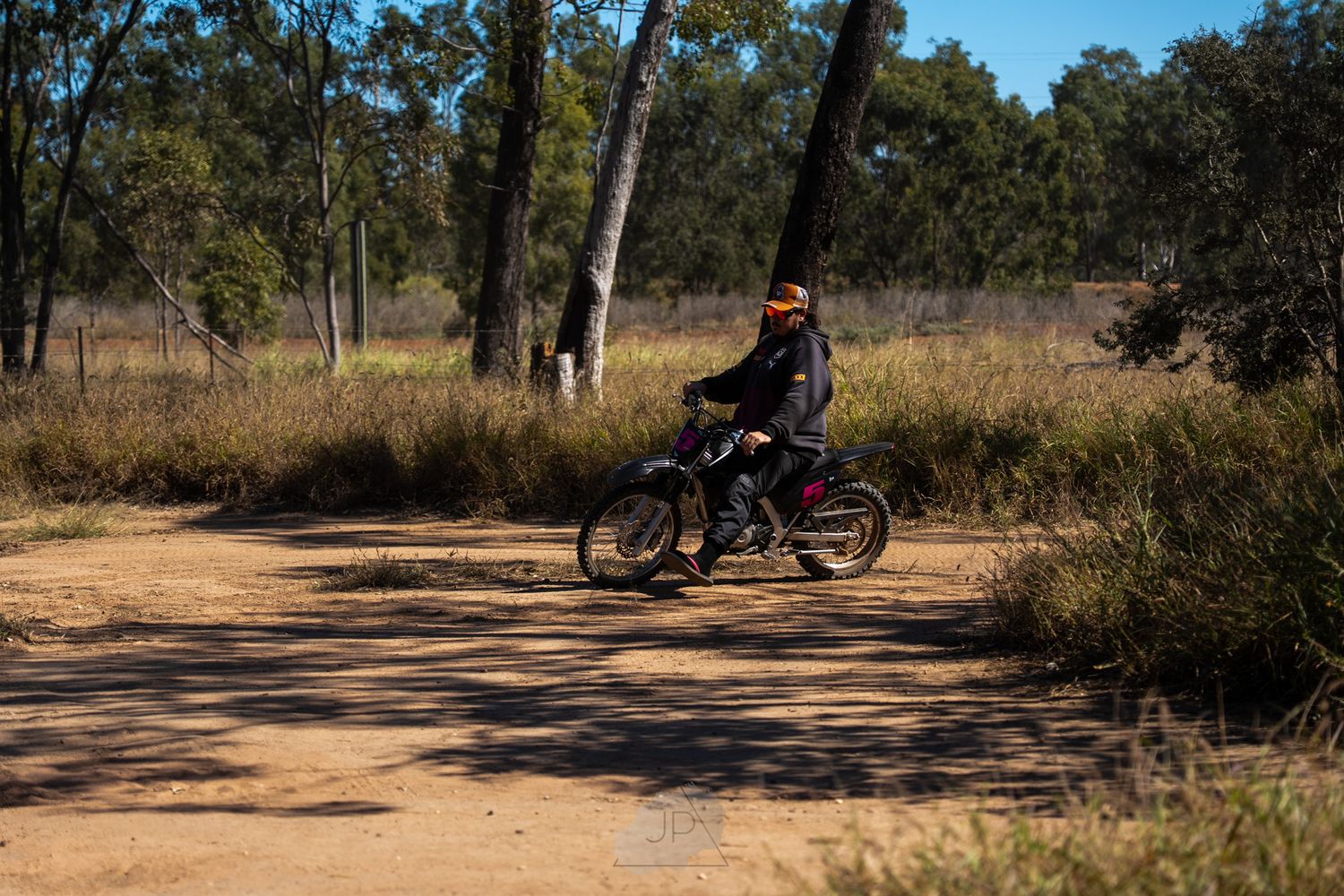 Mountain biker rides along a dirt trail through scenic bushland on a sunny afternoon.
