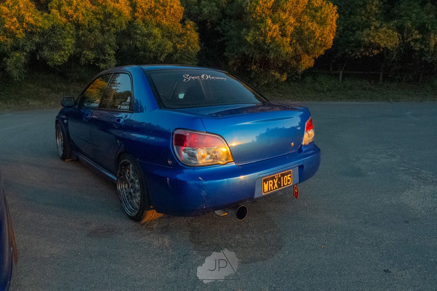 Modified blue Subaru Impreza WRX shown at various angles with fall foliage backdrop in a parking lot.