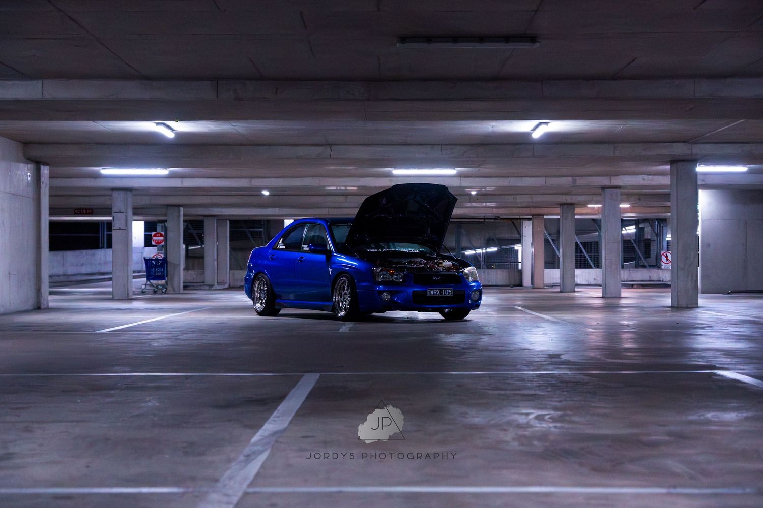 Several views of an underground parking garage with concrete columns and a blue car visible in different spots.