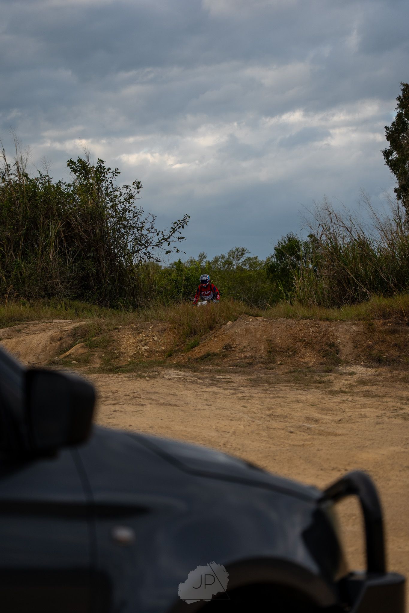 Dramatic cloudy sky view over a dirt path with shadows casting across the terrain.
