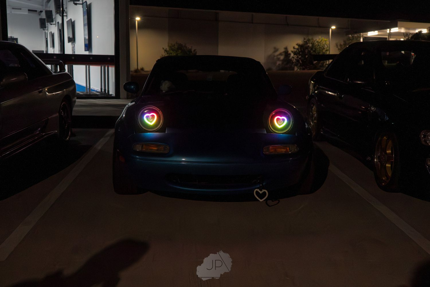 A BMW M3 vehicle parked at night with glowing headlights illuminating the darkness.