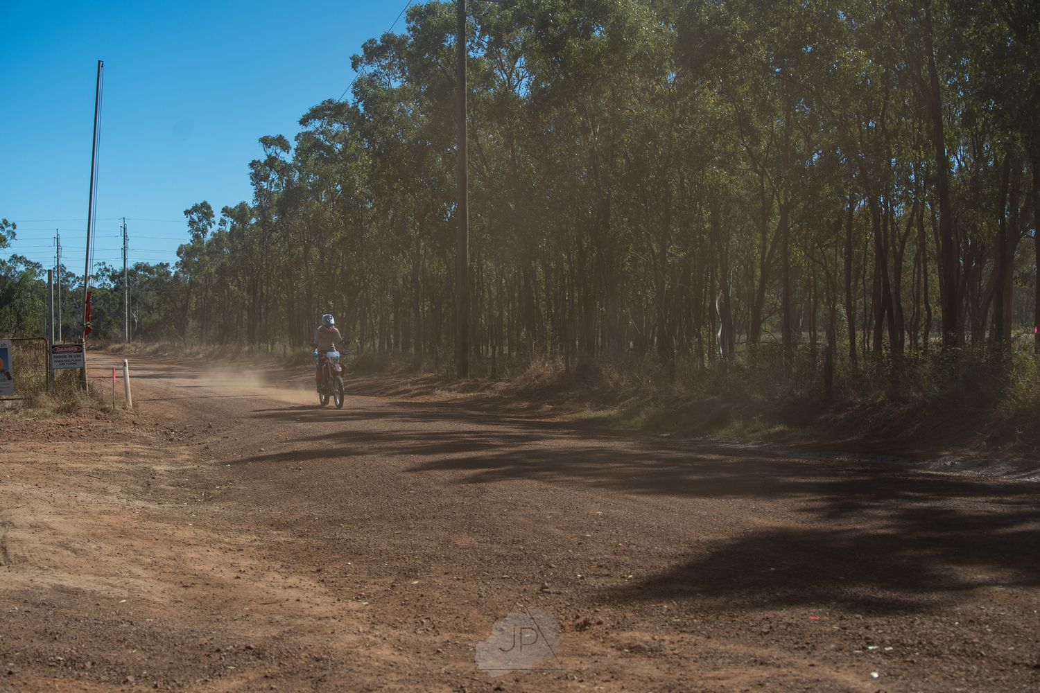 A series of interconnected dirt trails winding through a wooded forest area with scattered trees and dry ground.