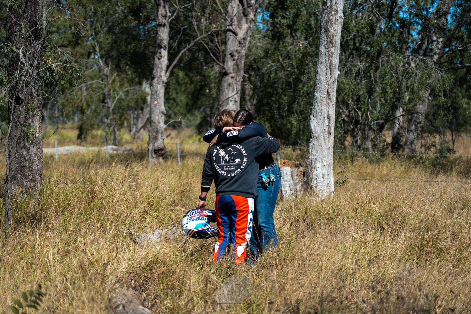 Mountain biker riding on single track dirt trail through eucalyptus forest with backpack during sunny day.