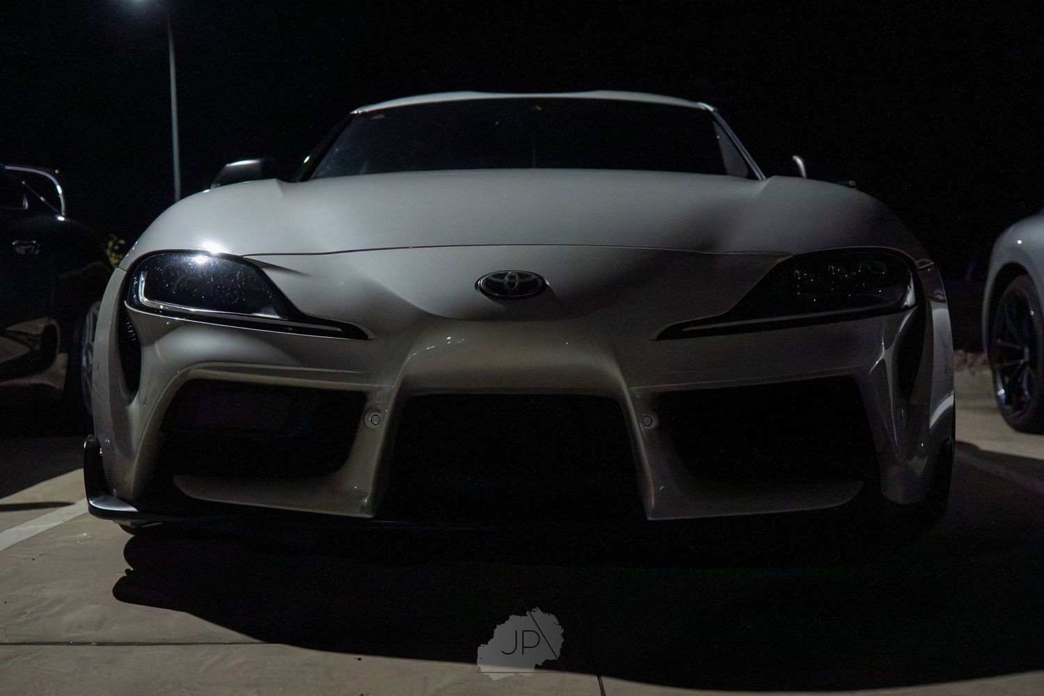 Dark luxury sports car front and side views showcasing sleek silhouette and aggressive styling details in low light.