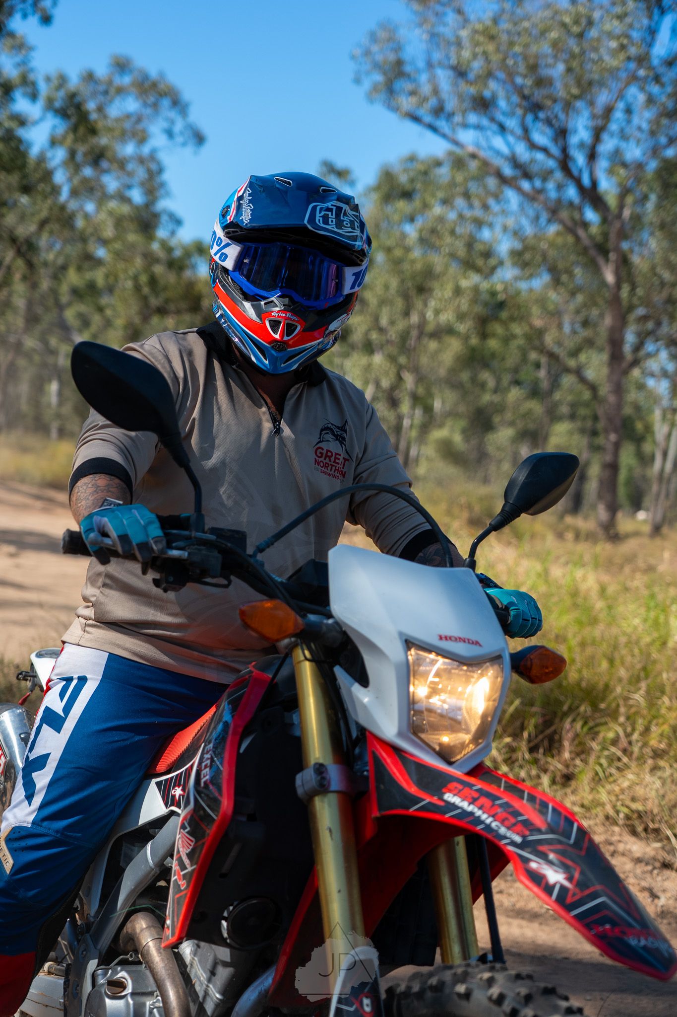 Rider on red and white dirt bike motorcycle shown in sequence of action shots through wooded trail area during daytime.