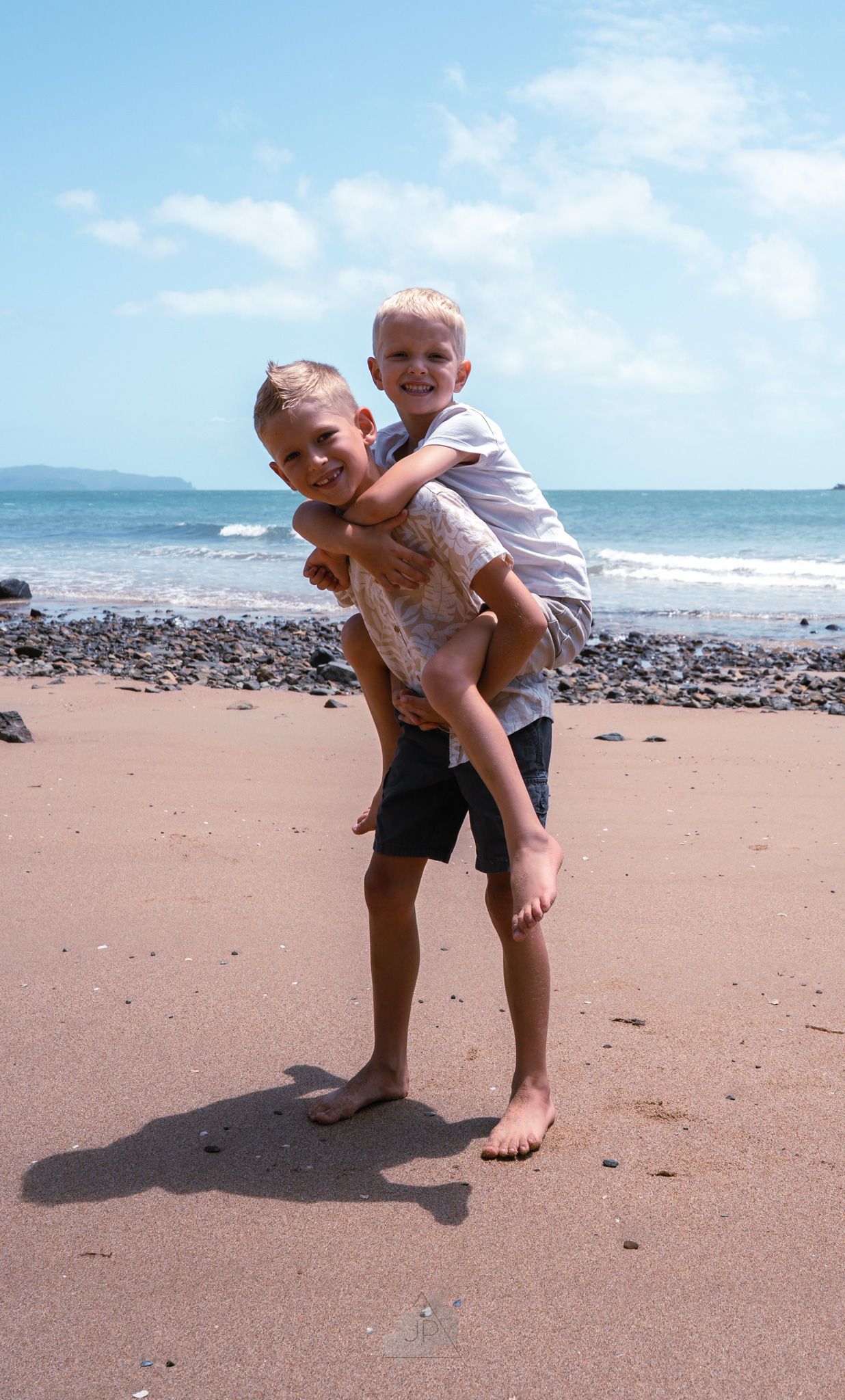A sequence of photos shows a playful moment at a scenic beach with rocky shoreline and blue ocean waters in the background.