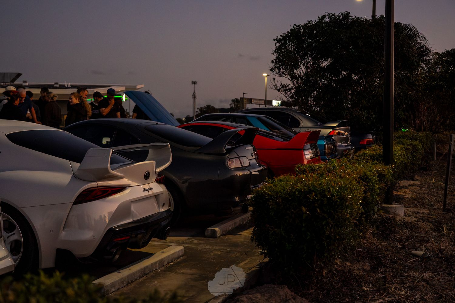 Multiple cars parked at sunset in a parking lot with dramatic lighting and shadows.