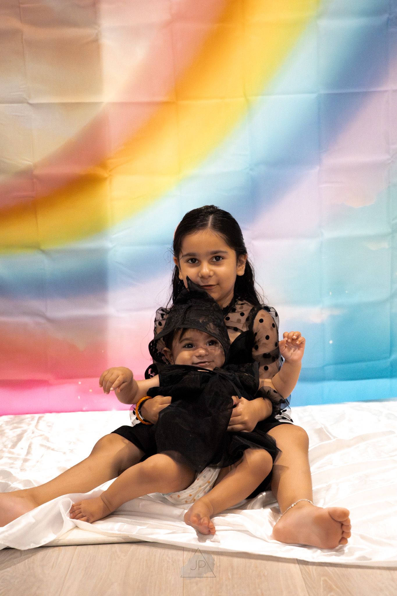 Sequence of photos showing a baby lying on white fabric against a colorful rainbow backdrop.