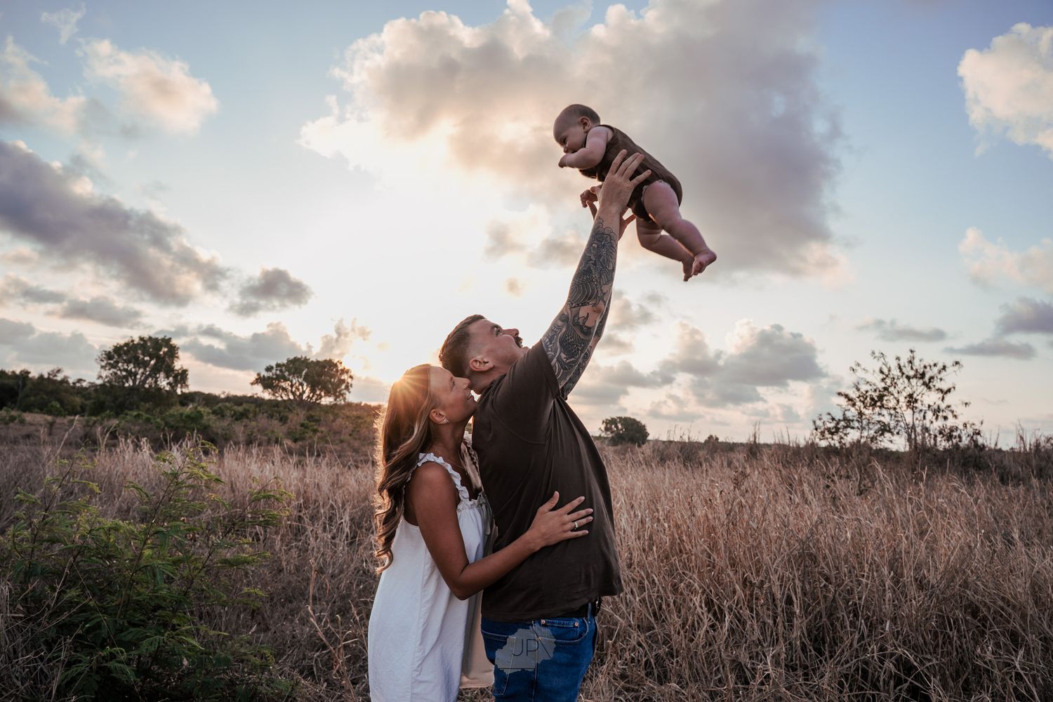 A couple shares tender moments in a golden field at sunset during a romantic photoshoot.