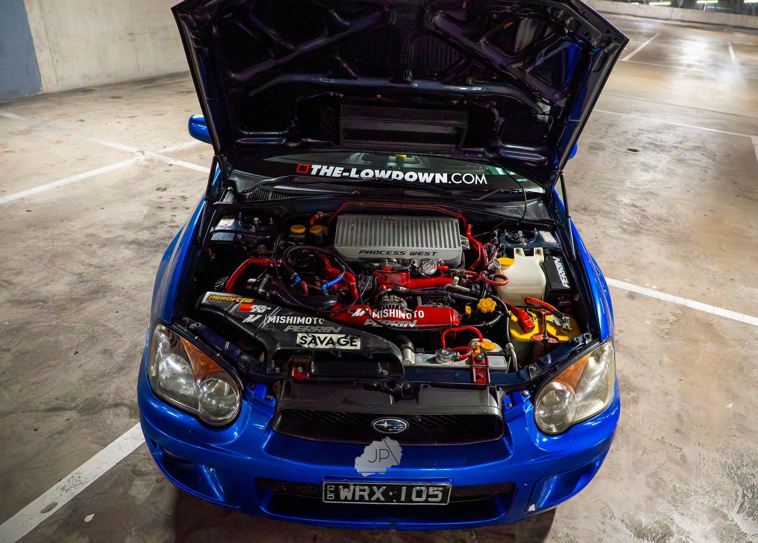 Multiple views of a blue modified Subaru WRX with exposed engine bay showcasing performance upgrades and modifications.