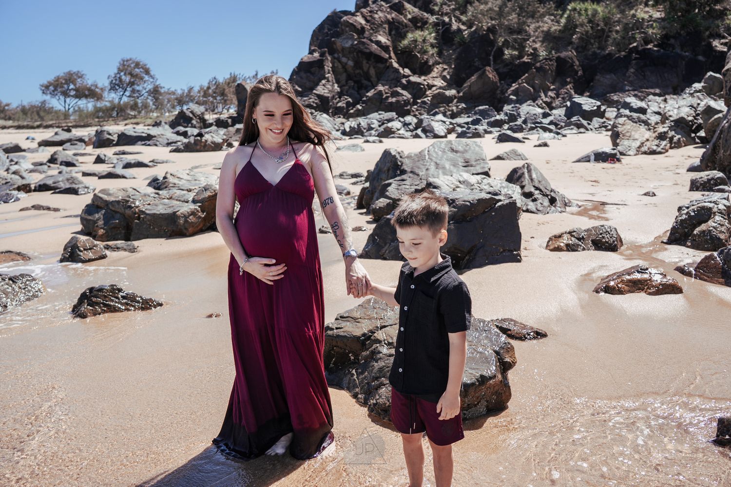 A family enjoys a sunny day exploring the rocky coastline and sandy beach together.