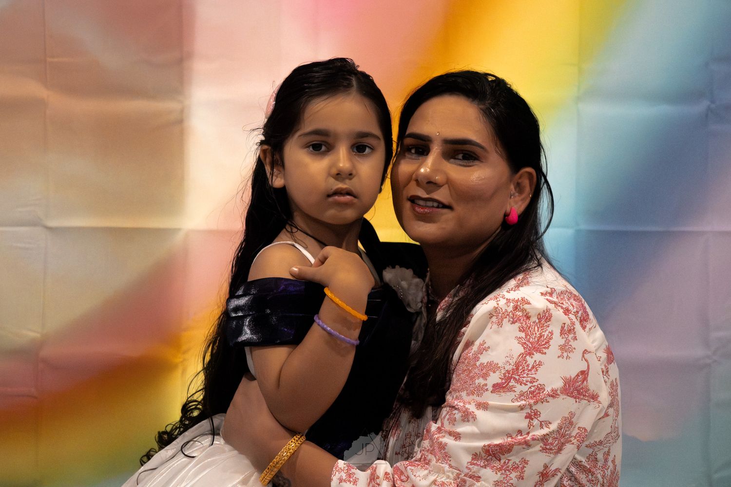Mother and daughter share a tender moment together while sitting in a room with warm lighting.