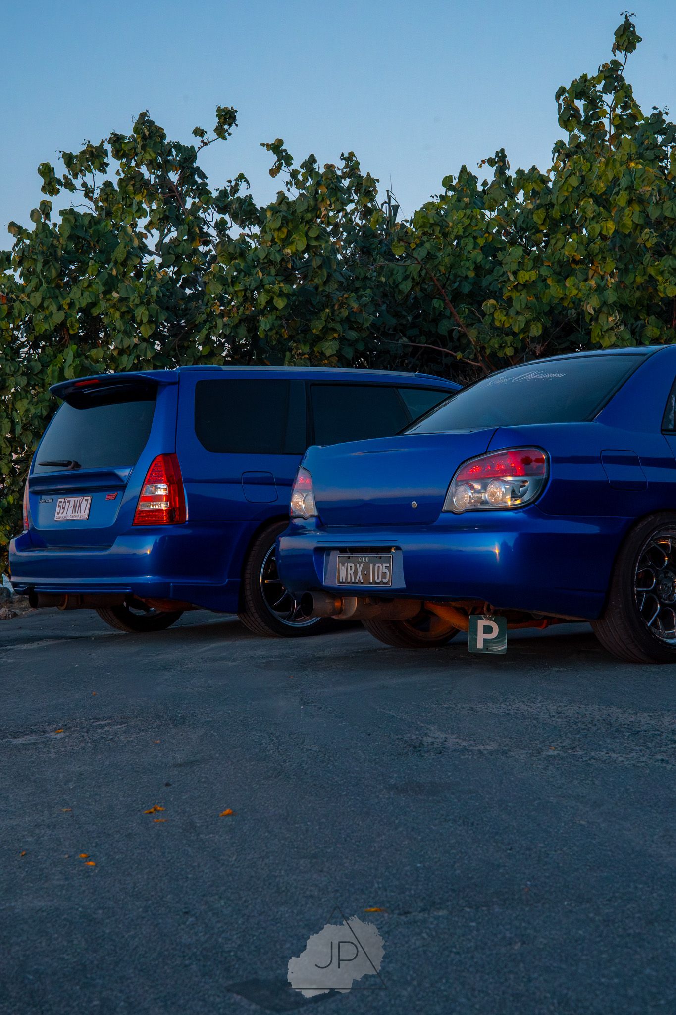 A row of identical blue 2002-2007 Subaru WRX sedans parked together at a car meet.