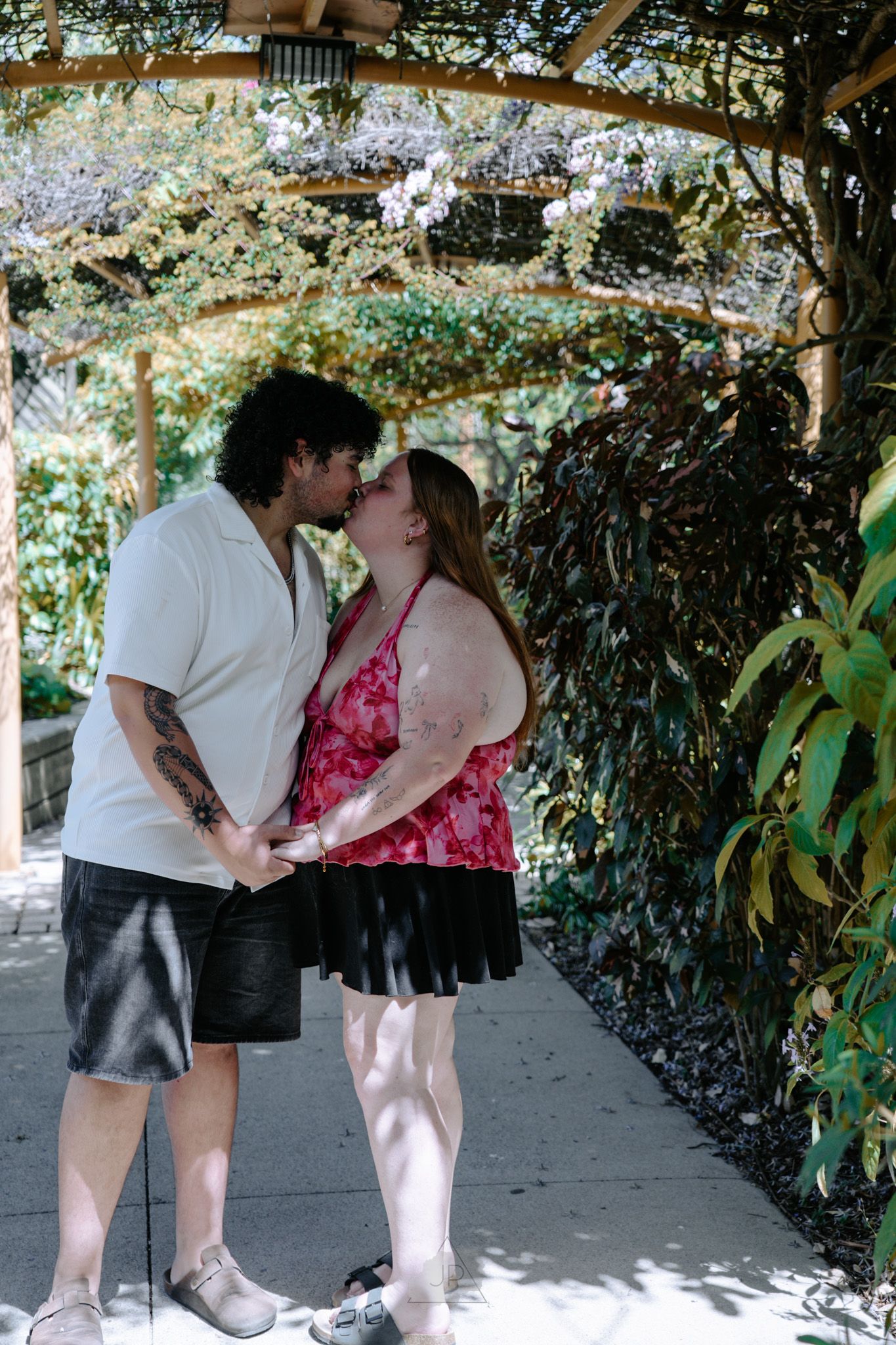 A couple shares a tender kiss under a leafy garden arbor in a series of romantic moments.