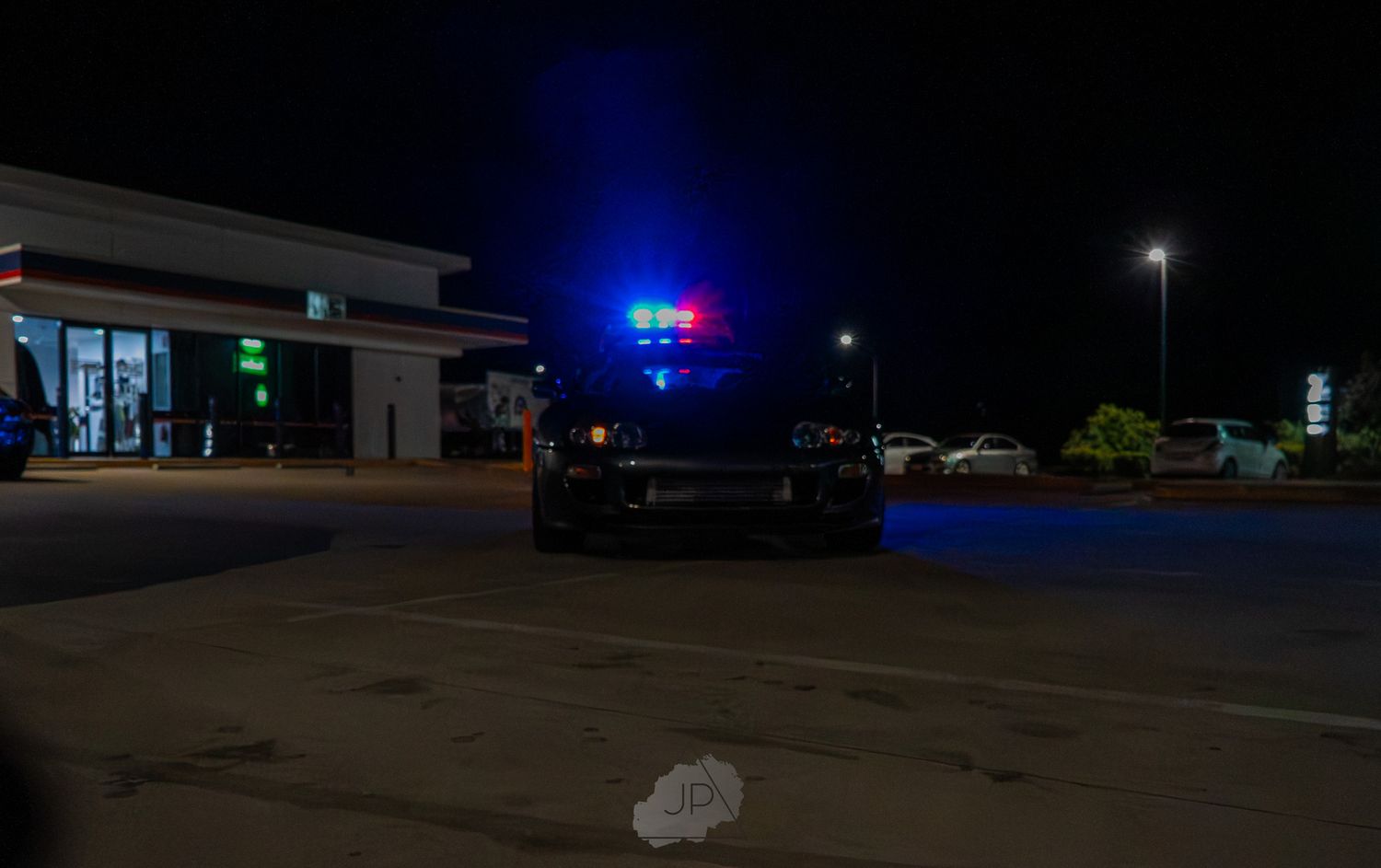 Surveillance footage showing empty parking lots and buildings illuminated by blue police lights at night.