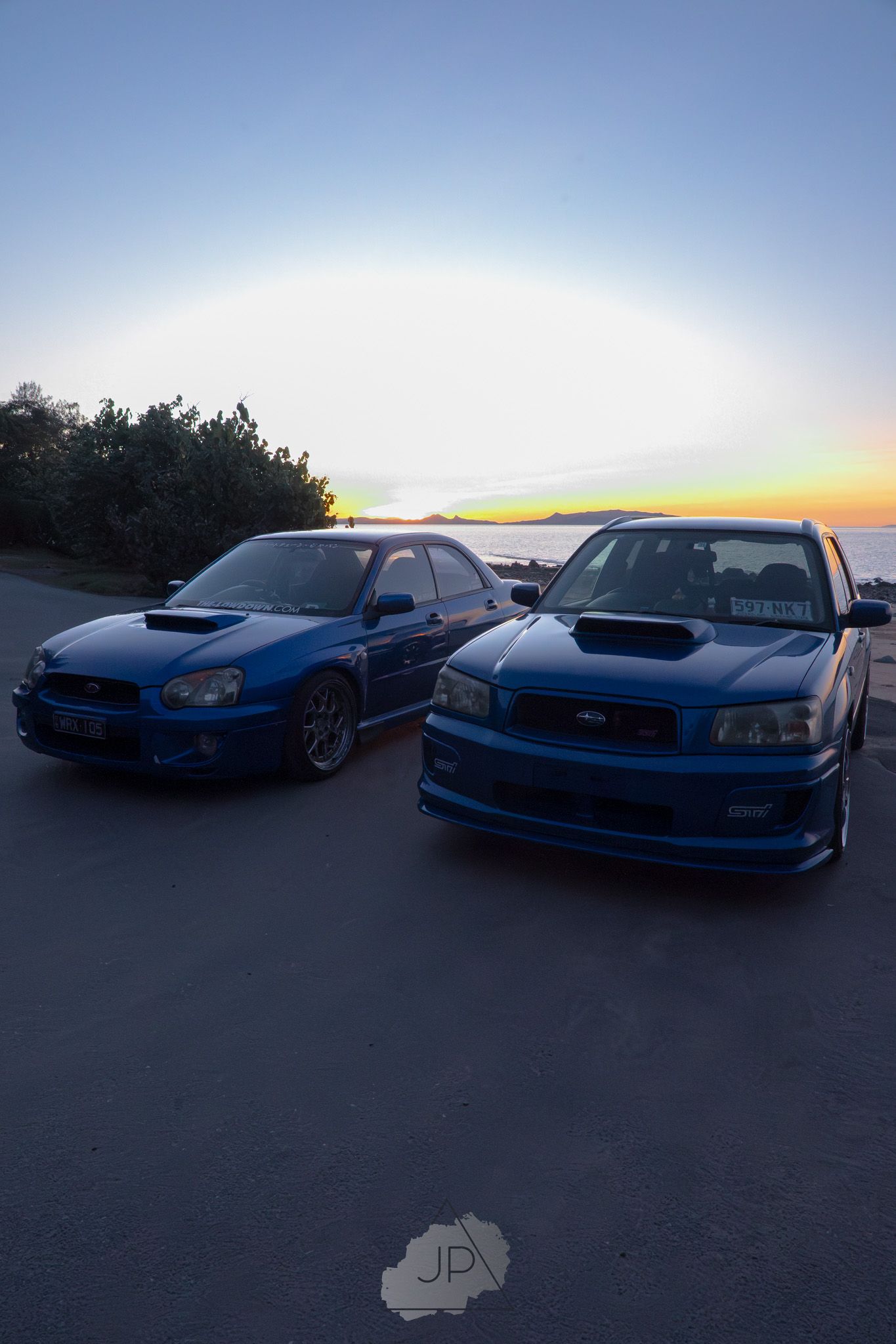 Row of custom Japanese performance cars showcasing their sleek profiles against a fading daylight sky.