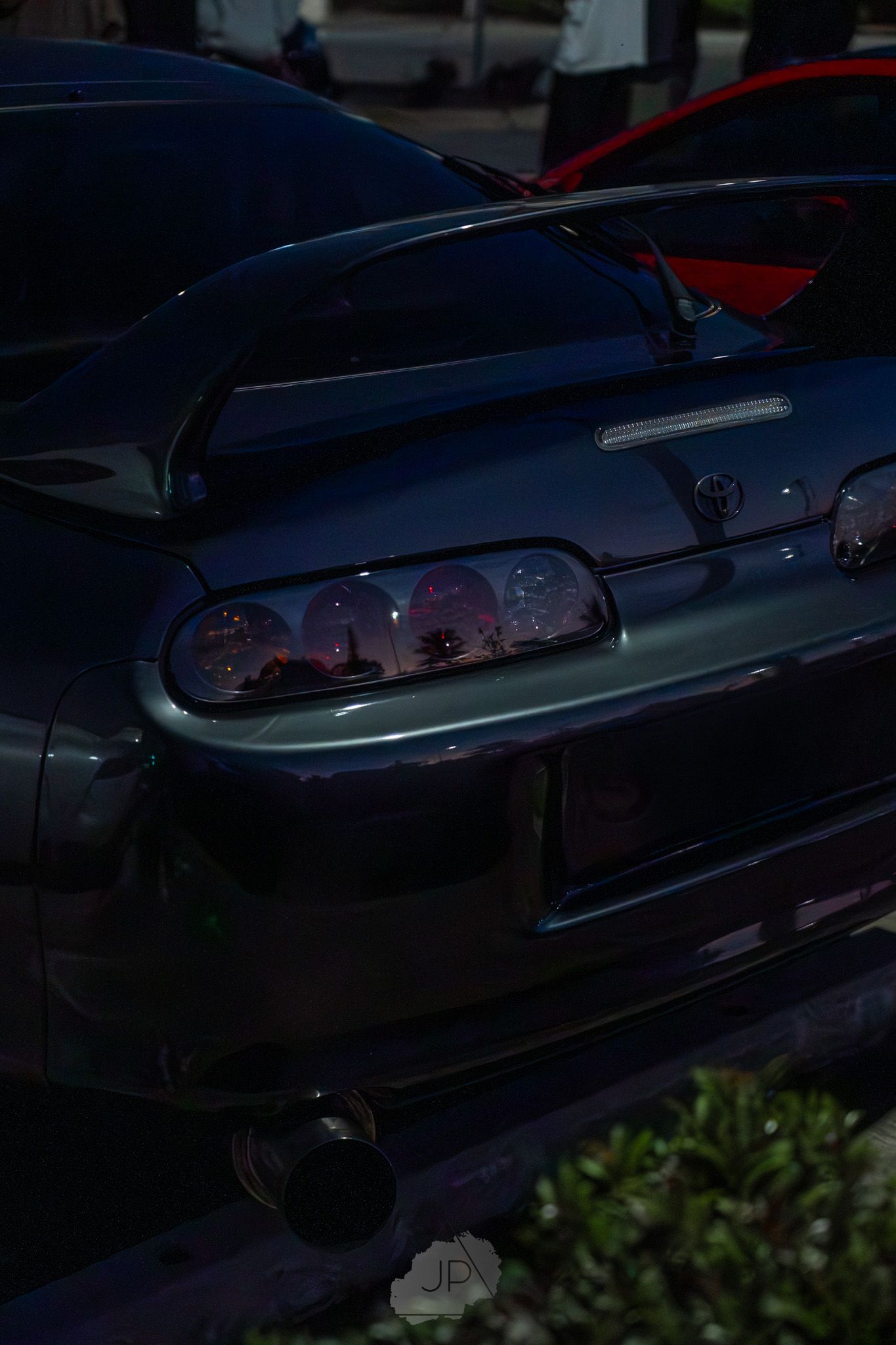 Dark blue vintage car detail showing part of the hood and side body panel in evening light.