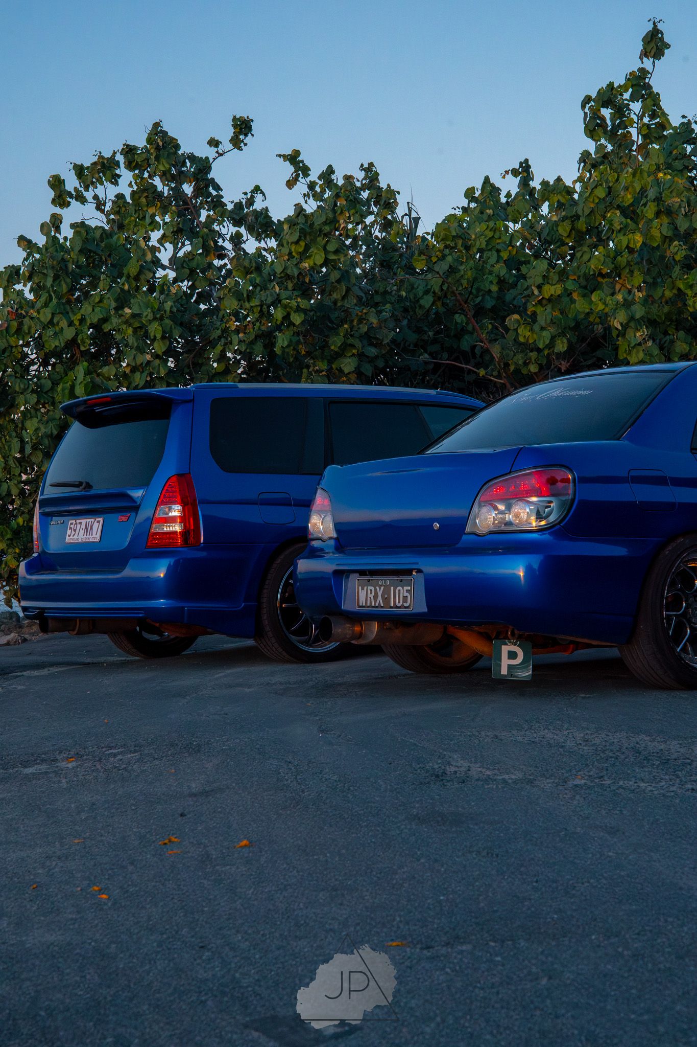 Blue Honda Civic cars parked in a row at sunset showcasing similar modified vehicles in an outdoor parking area.