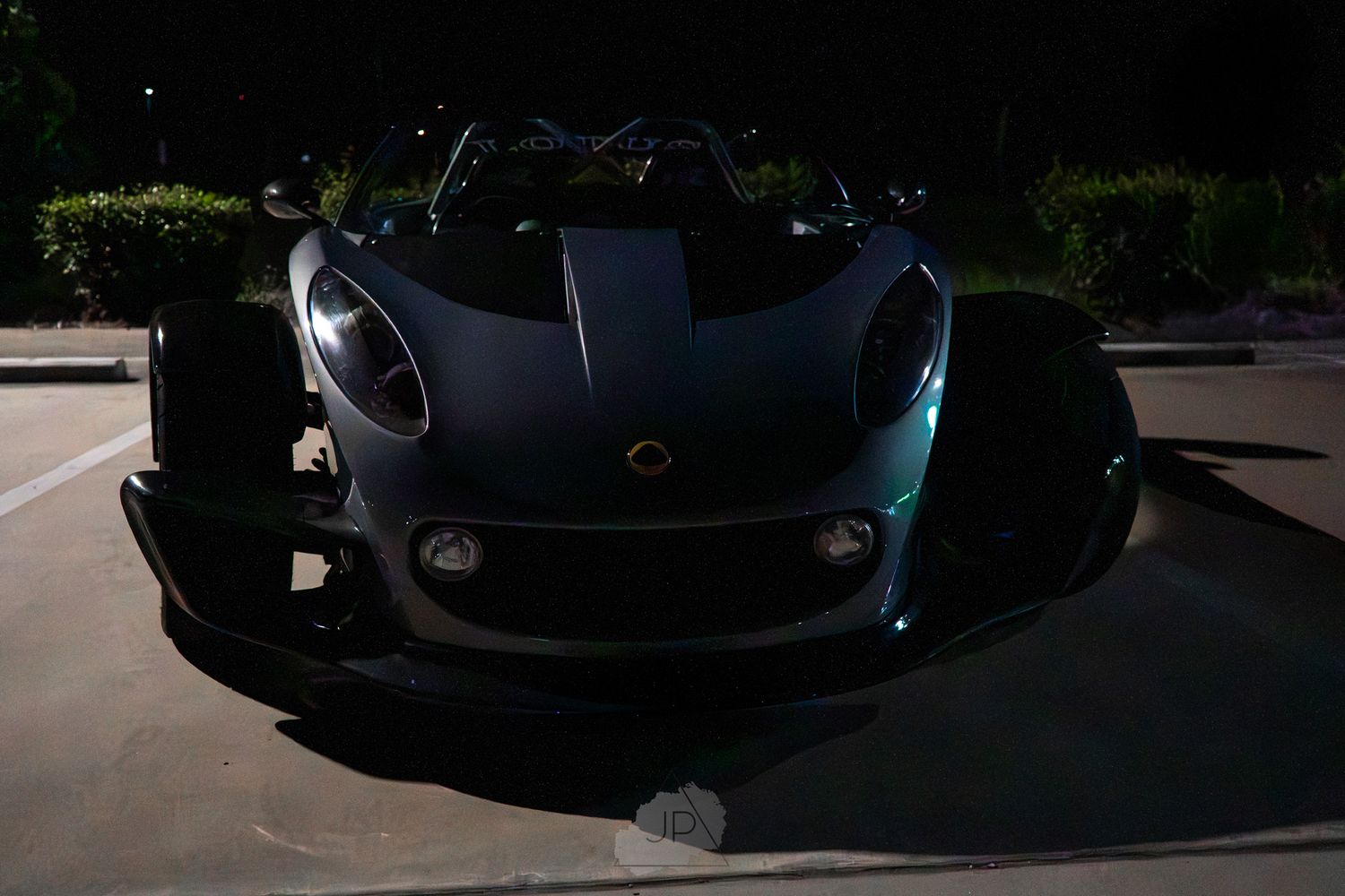 Black luxury sports car photographed in low light conditions showing sleek curves and aggressive styling details.