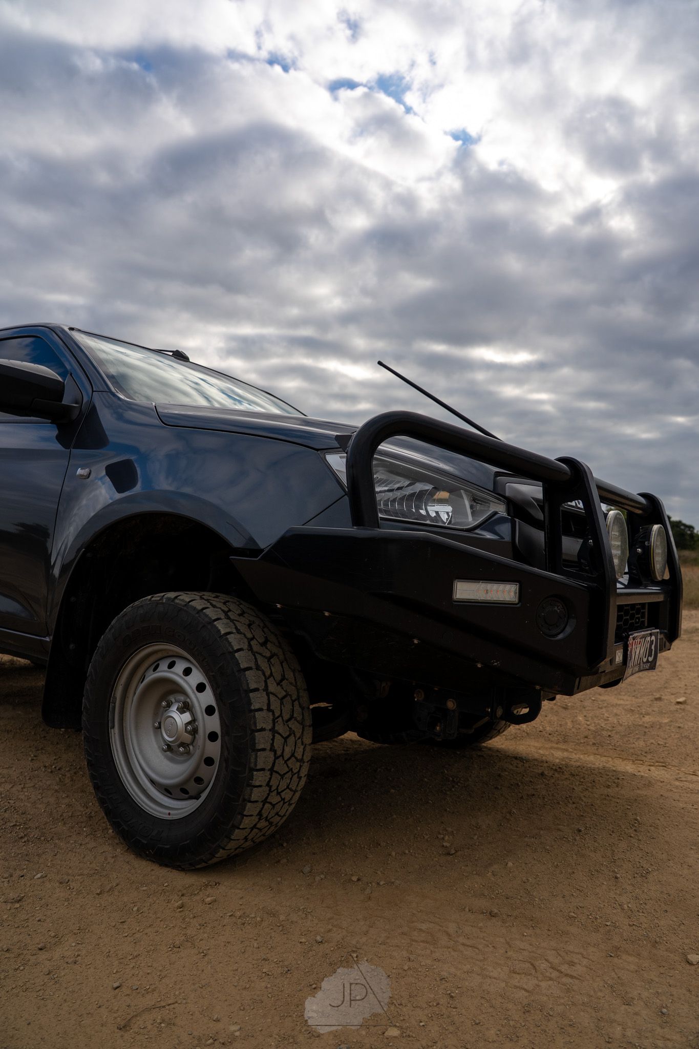 Black off-road vehicles lined up at a low angle showing rugged tires and modified bumper guards against cloudy skies.