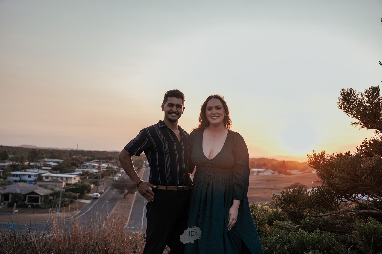 Silhouettes of people standing together against a dramatic orange and purple sunset sky at a scenic overlook.
