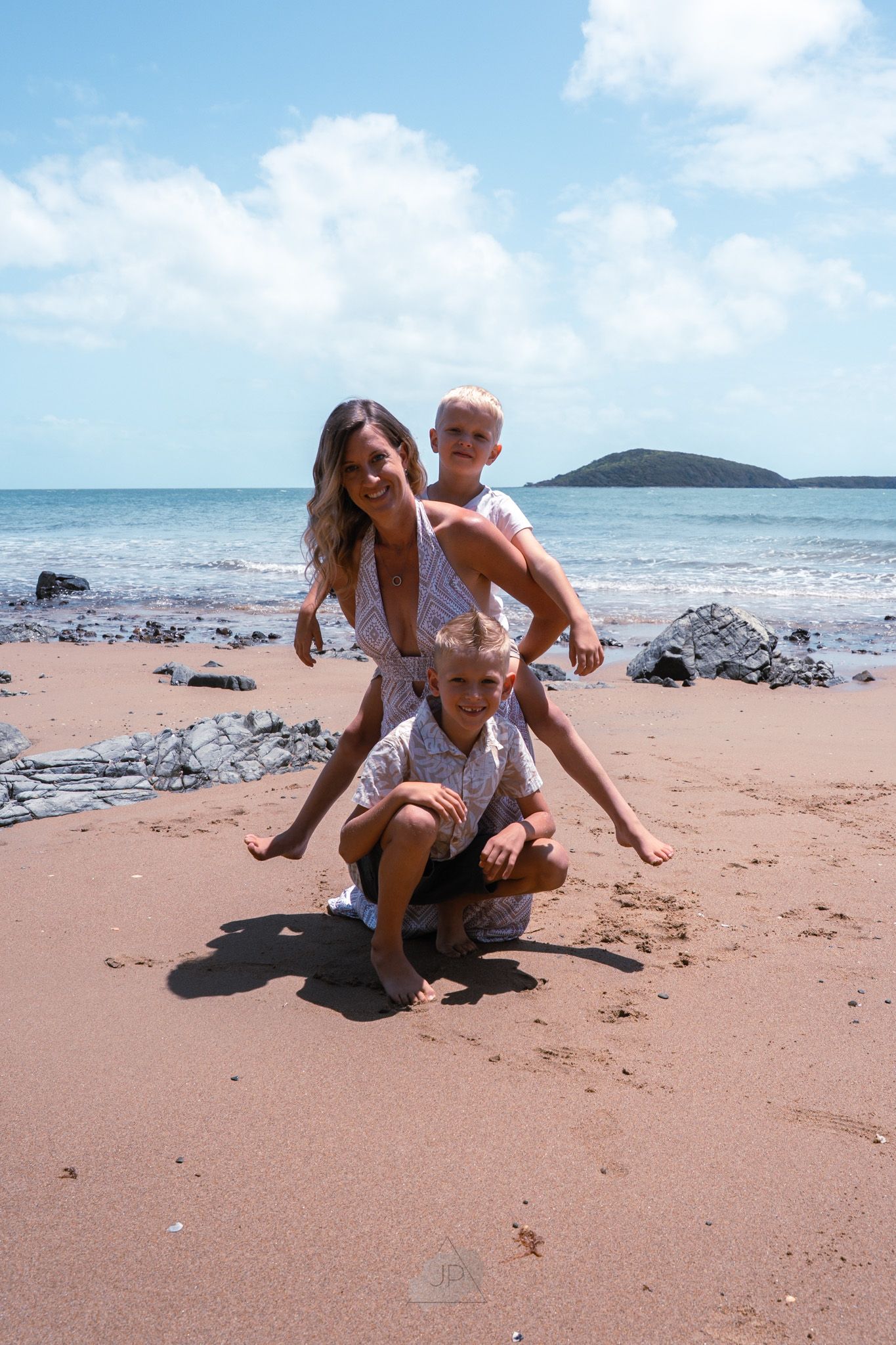 Playful interactions on a sandy beach with ocean waves and an island visible on the horizon.