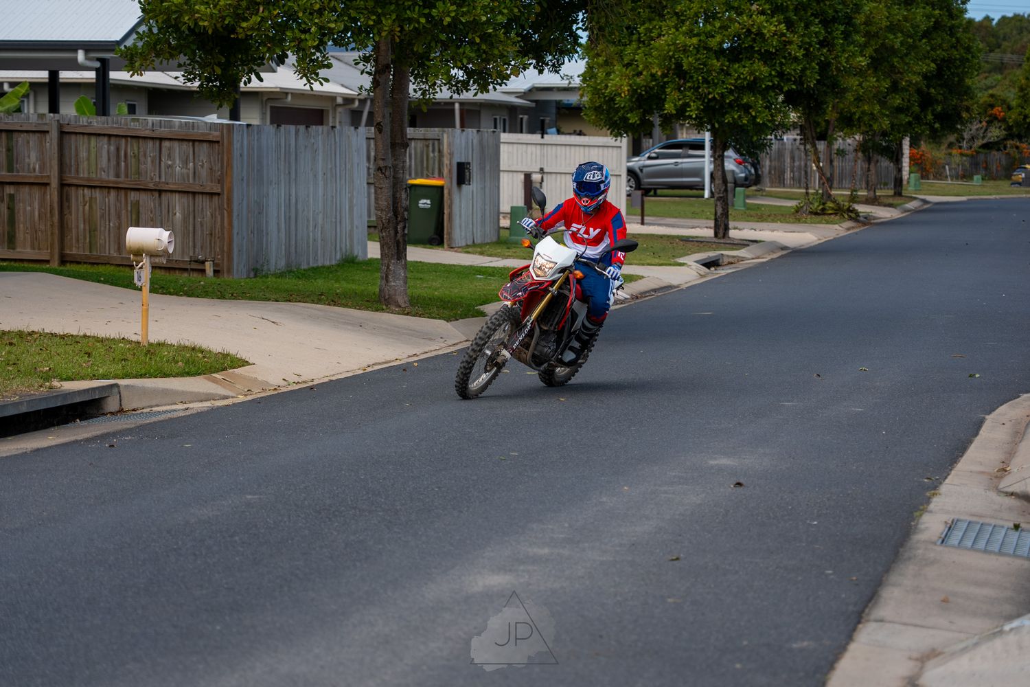 A skateboarder rolls down an empty residential street, performing tricks and maneuvers.