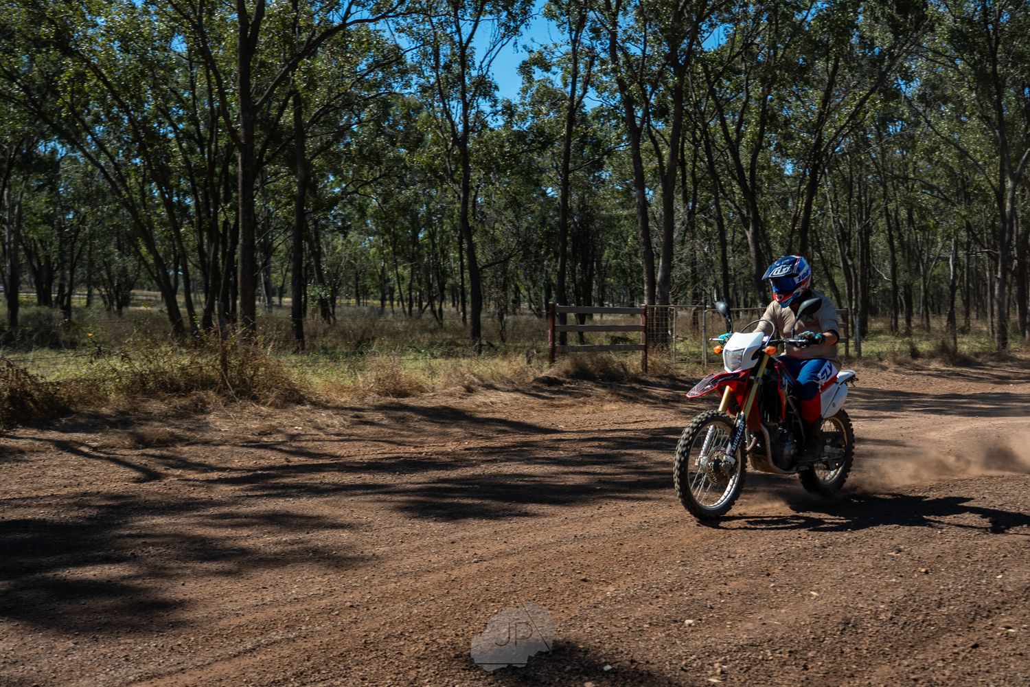 Multiple dirt bikes riding through an Australian bush track surrounded by eucalyptus trees.