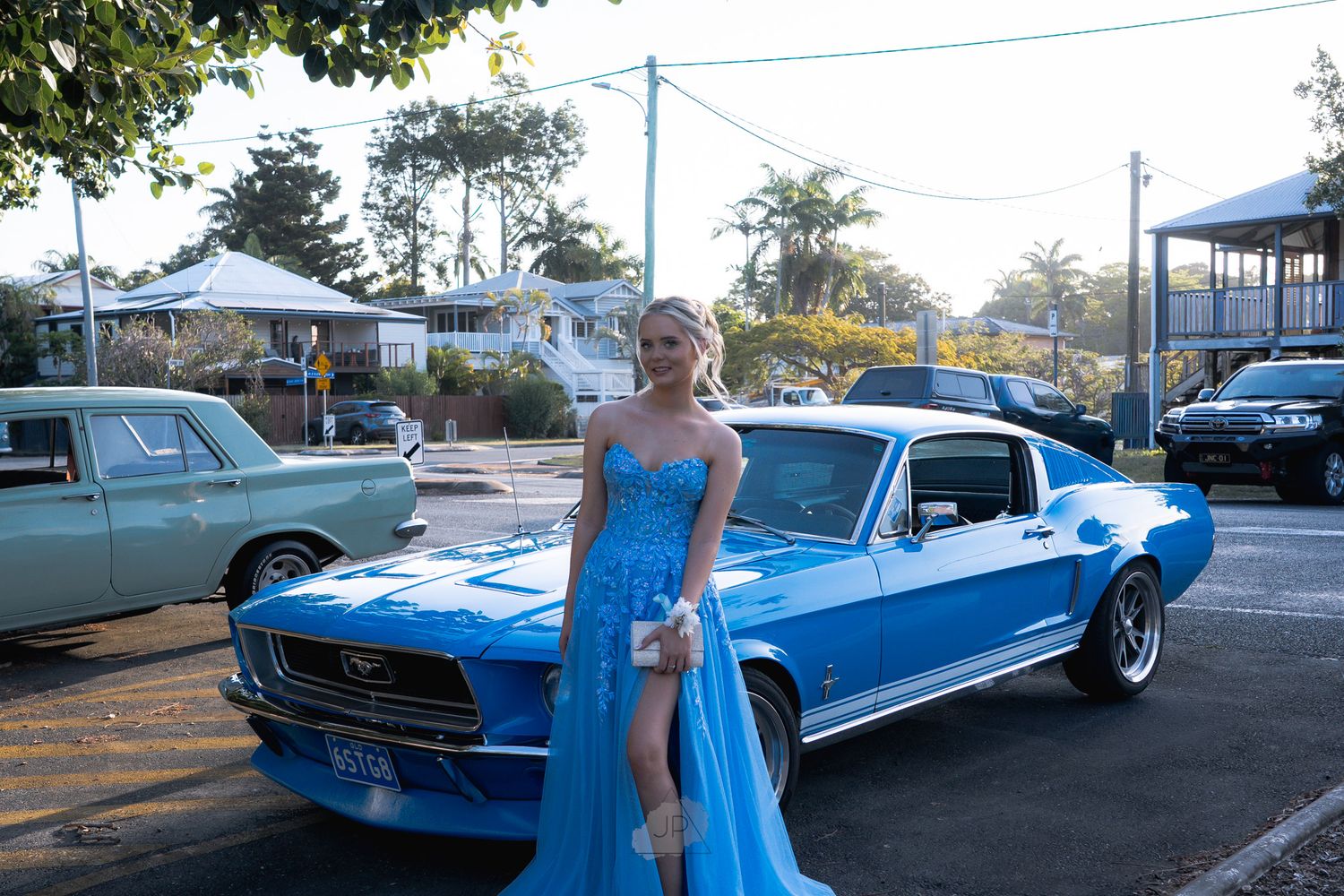 Classic blue Ford Mustang GT500 displayed at outdoor car show with other vintage vehicles in background.