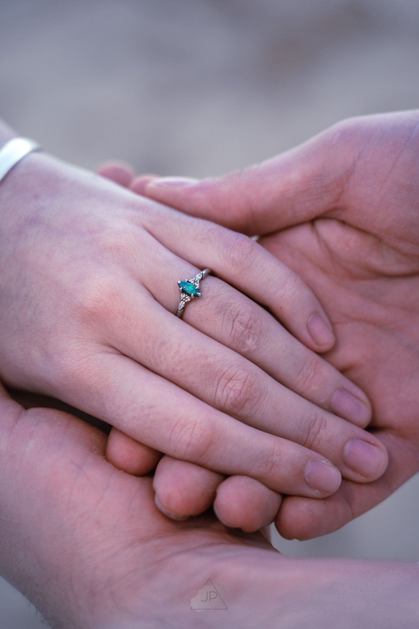Close-up shot of two hands gently clasped together with a delicate turquoise ring visible on one finger.