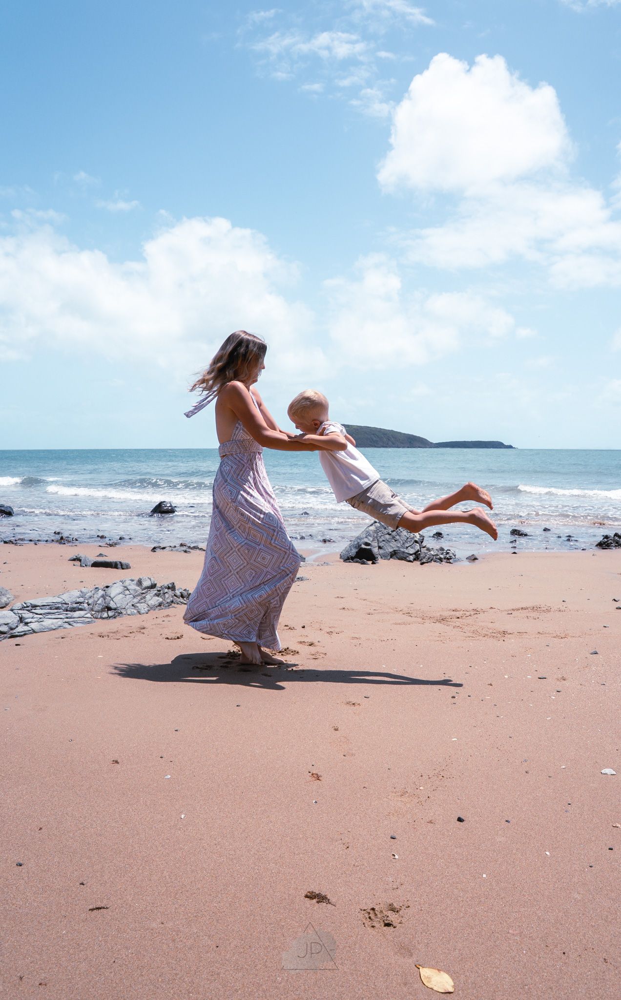 A sequence of photos showing someone falling backwards onto a sandy beach with blue ocean and sky in the background.