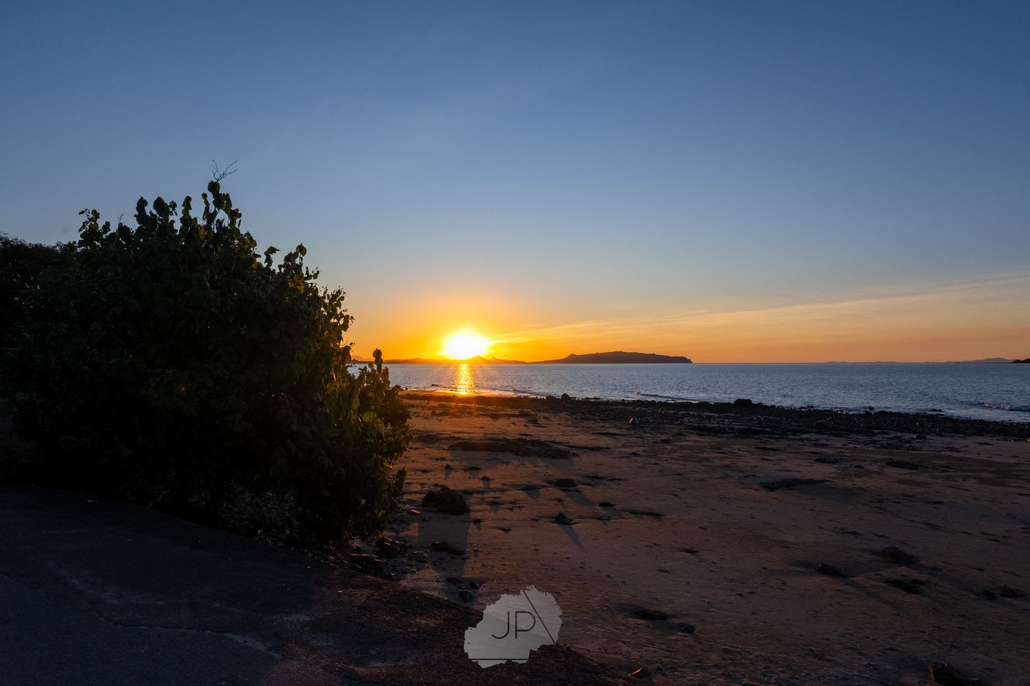 Various coastal sunset scenes along a rocky shoreline with vibrant orange and blue skies over a beach landscape.