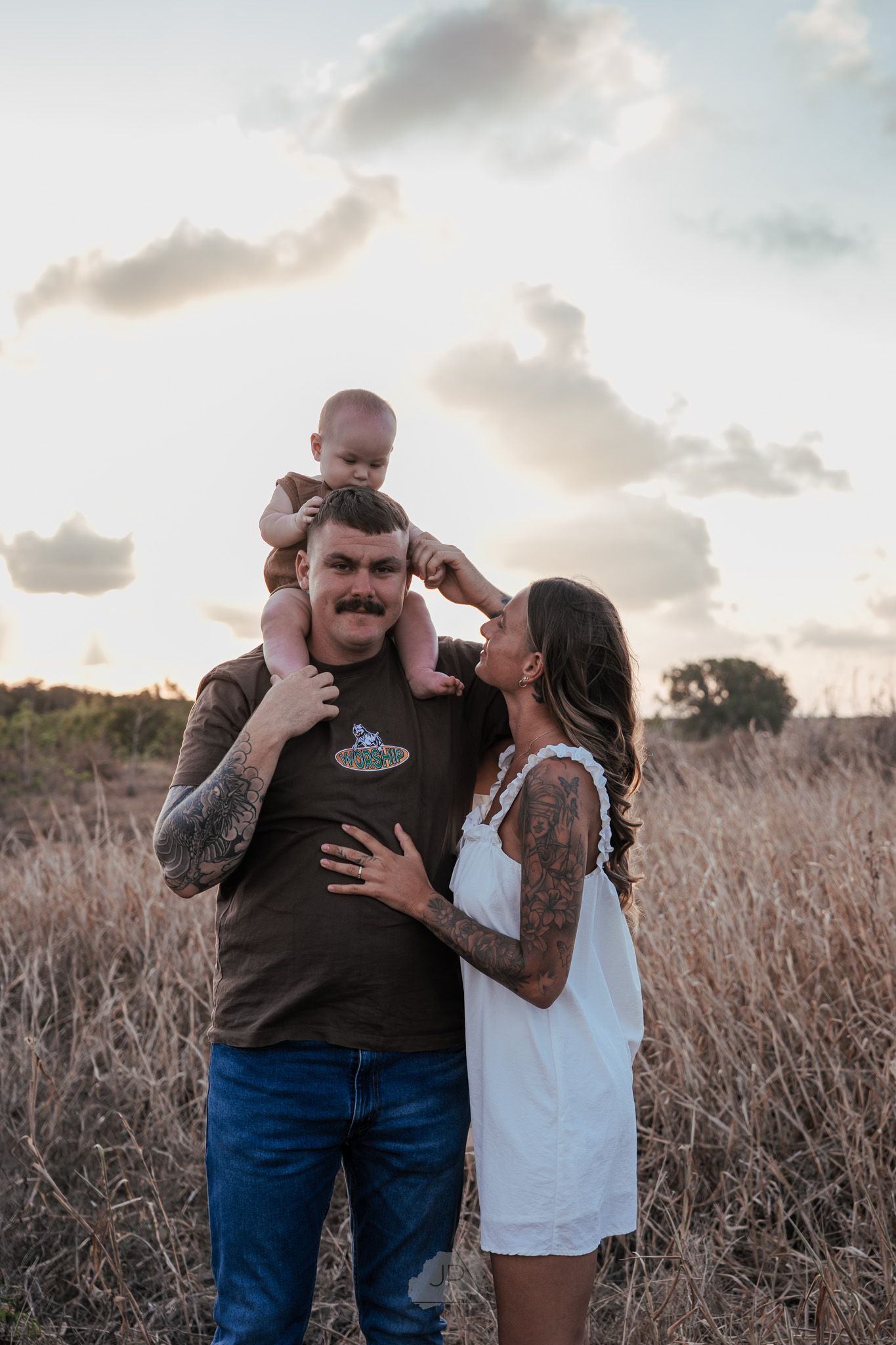 A family shares tender moments together in a golden field at sunset.