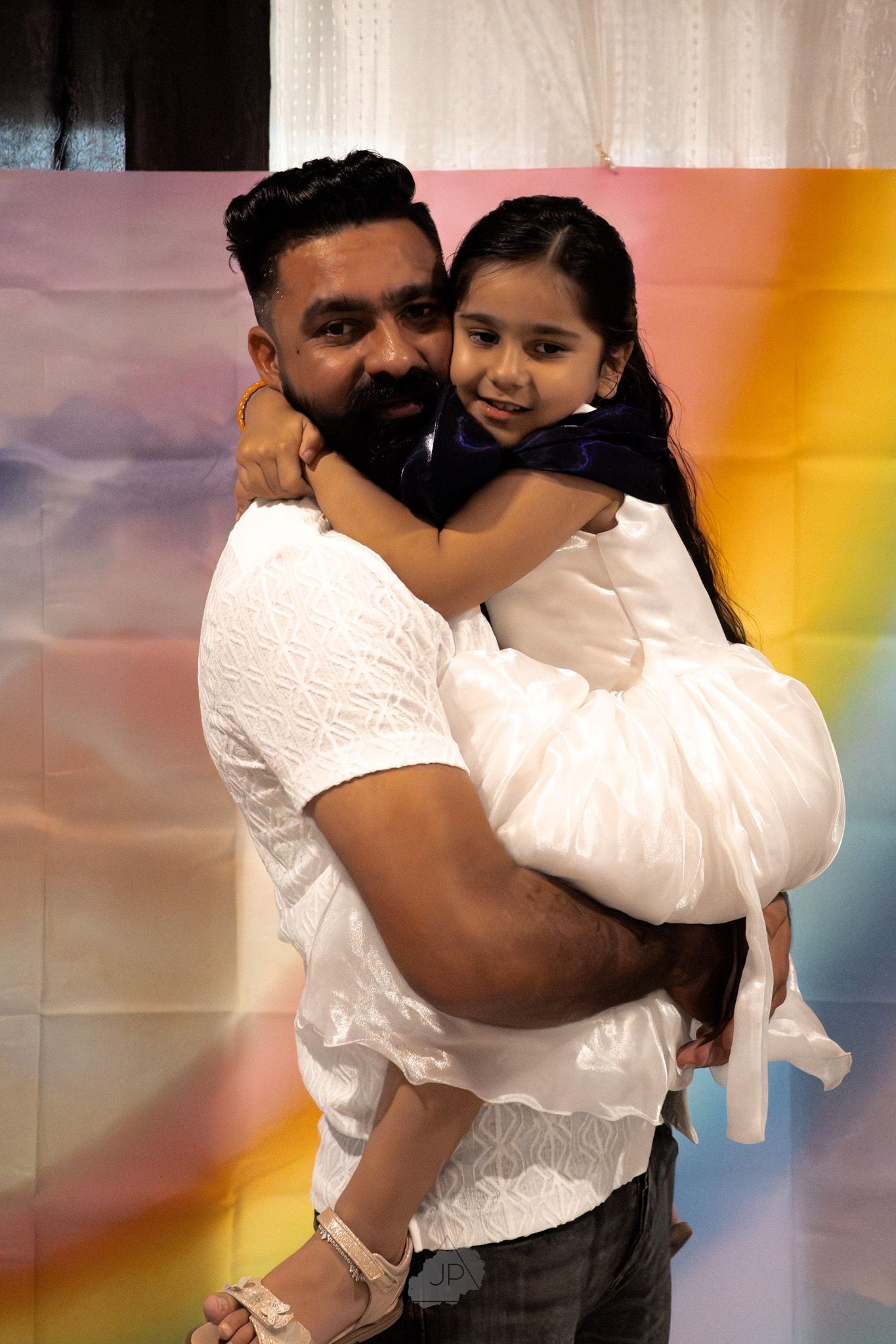 A couple embraces in a tender dance pose against a colorful gradient background.