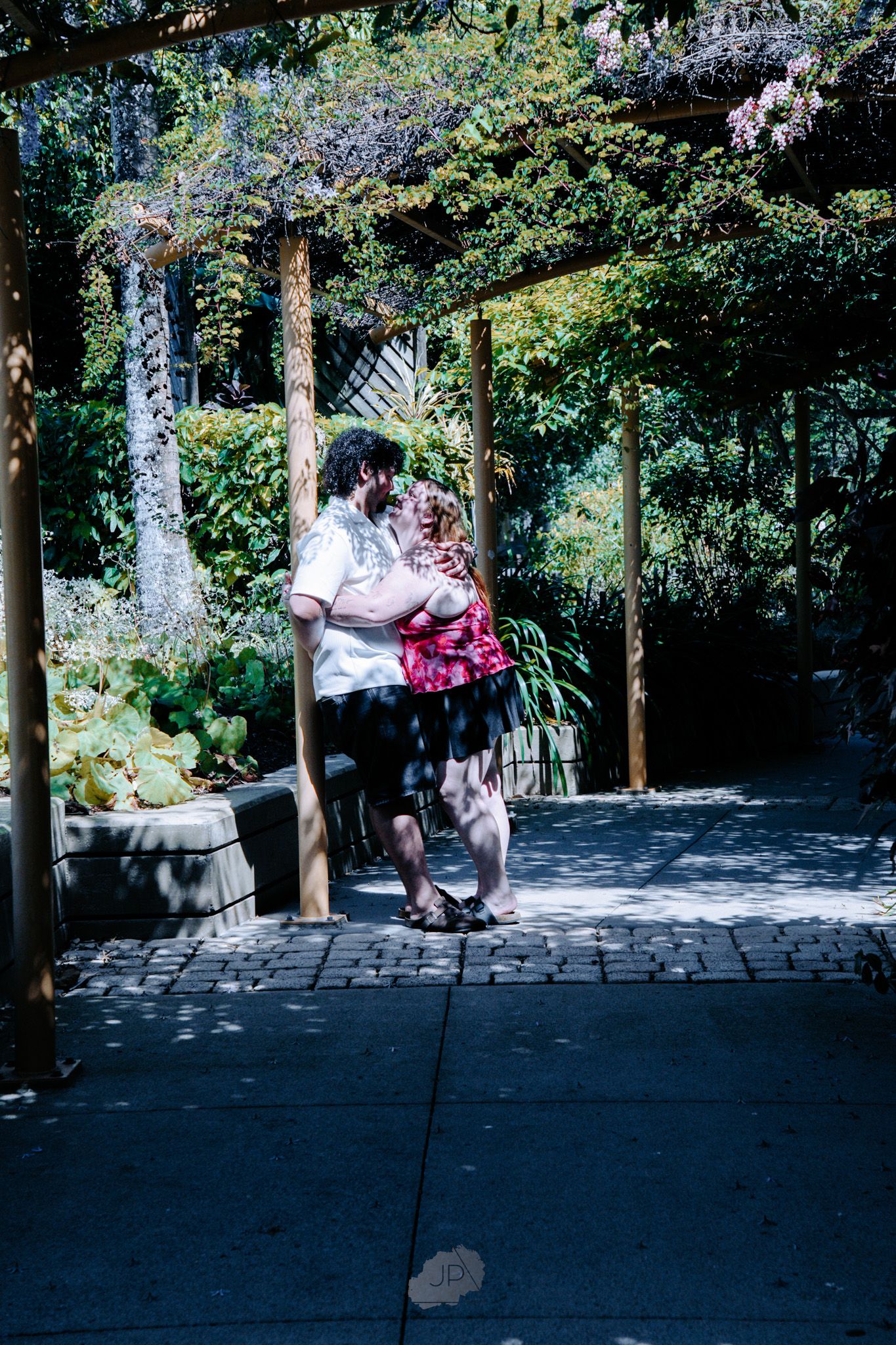 A romantic dance sequence captured in a lush garden setting with stone pathways and dappled sunlight.