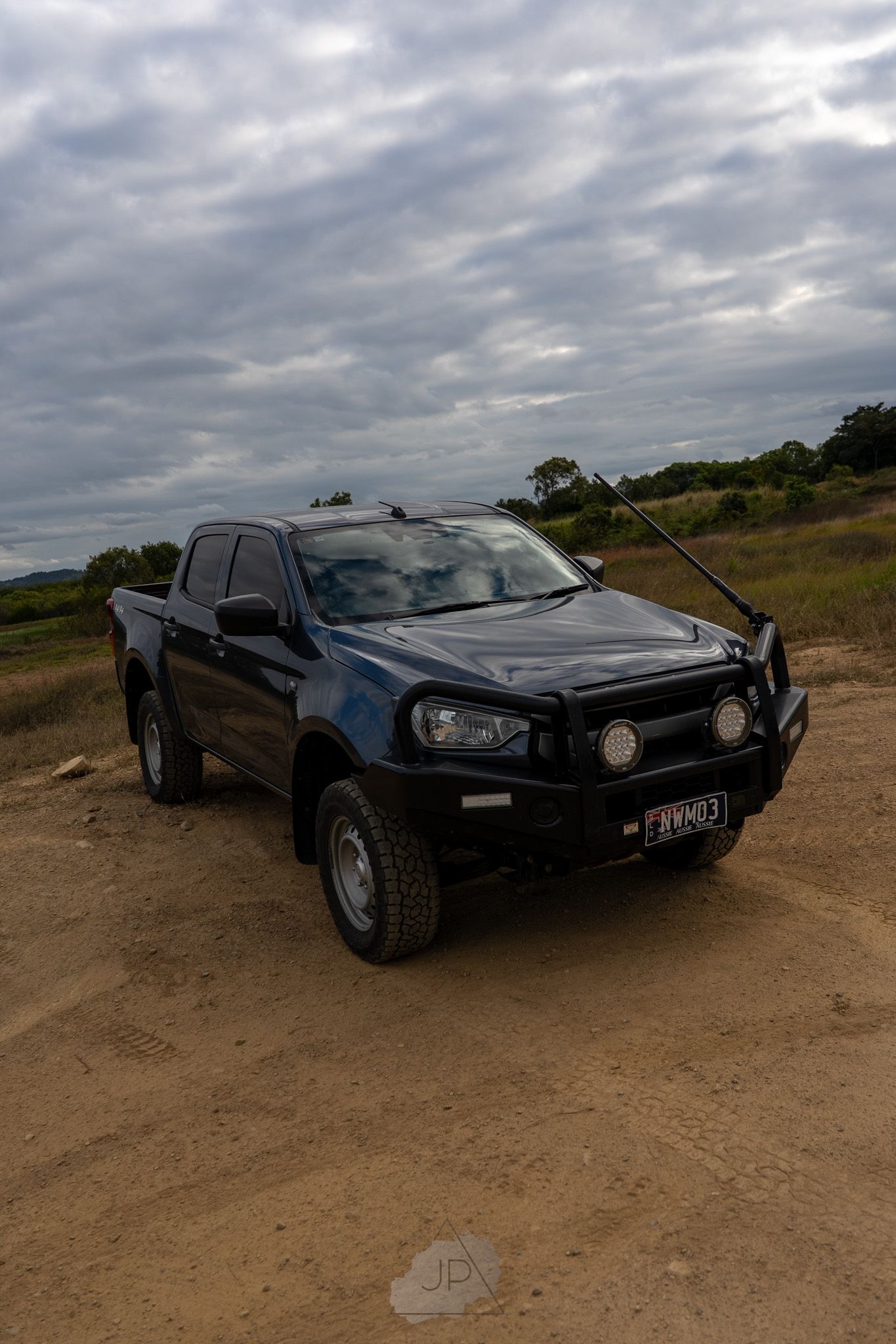Black sports car with sleek aerodynamic design photographed from multiple angles on dirt terrain under cloudy skies.