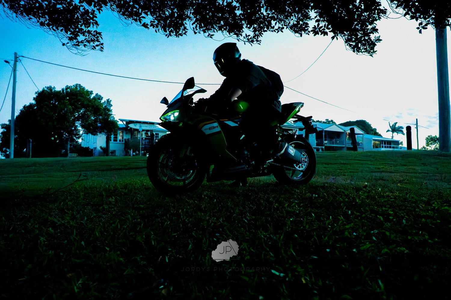 A silhouette of a person riding a motorcycle against a scenic blue sky background during sunset.