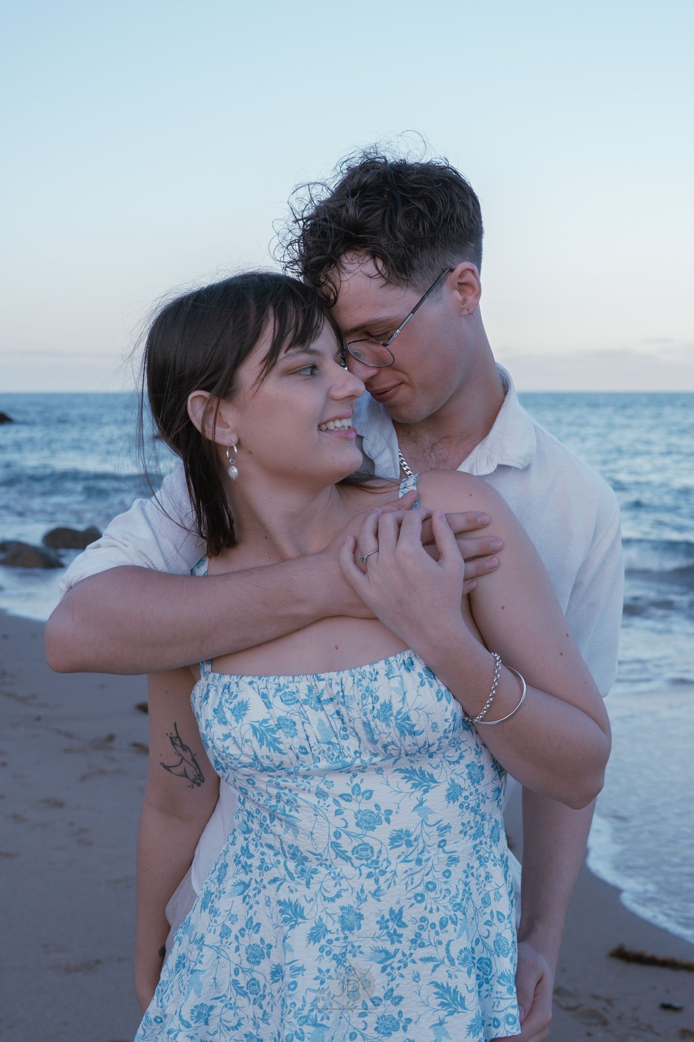 A tender moment between a couple on the beach as they share an intimate embrace near the ocean.