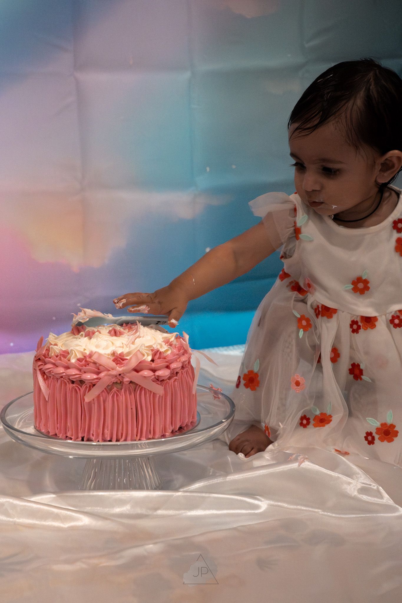 A sequence showing a pink frosted birthday cake being smashed and destroyed during a cake smash photo session.