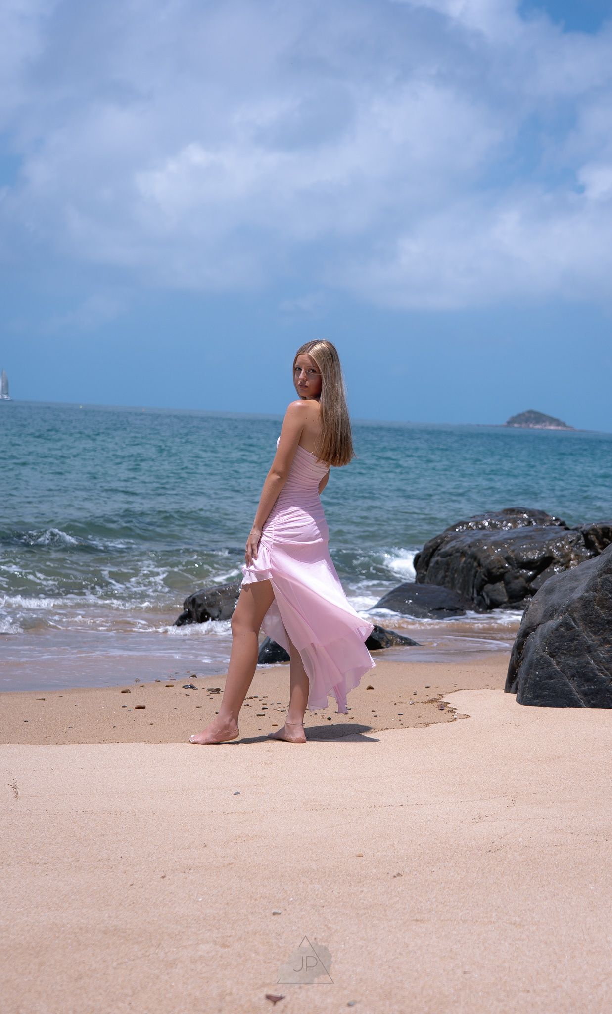 A series of photos showing a person in a pink dress sitting on a sandy beach with black rocks and blue ocean waves.