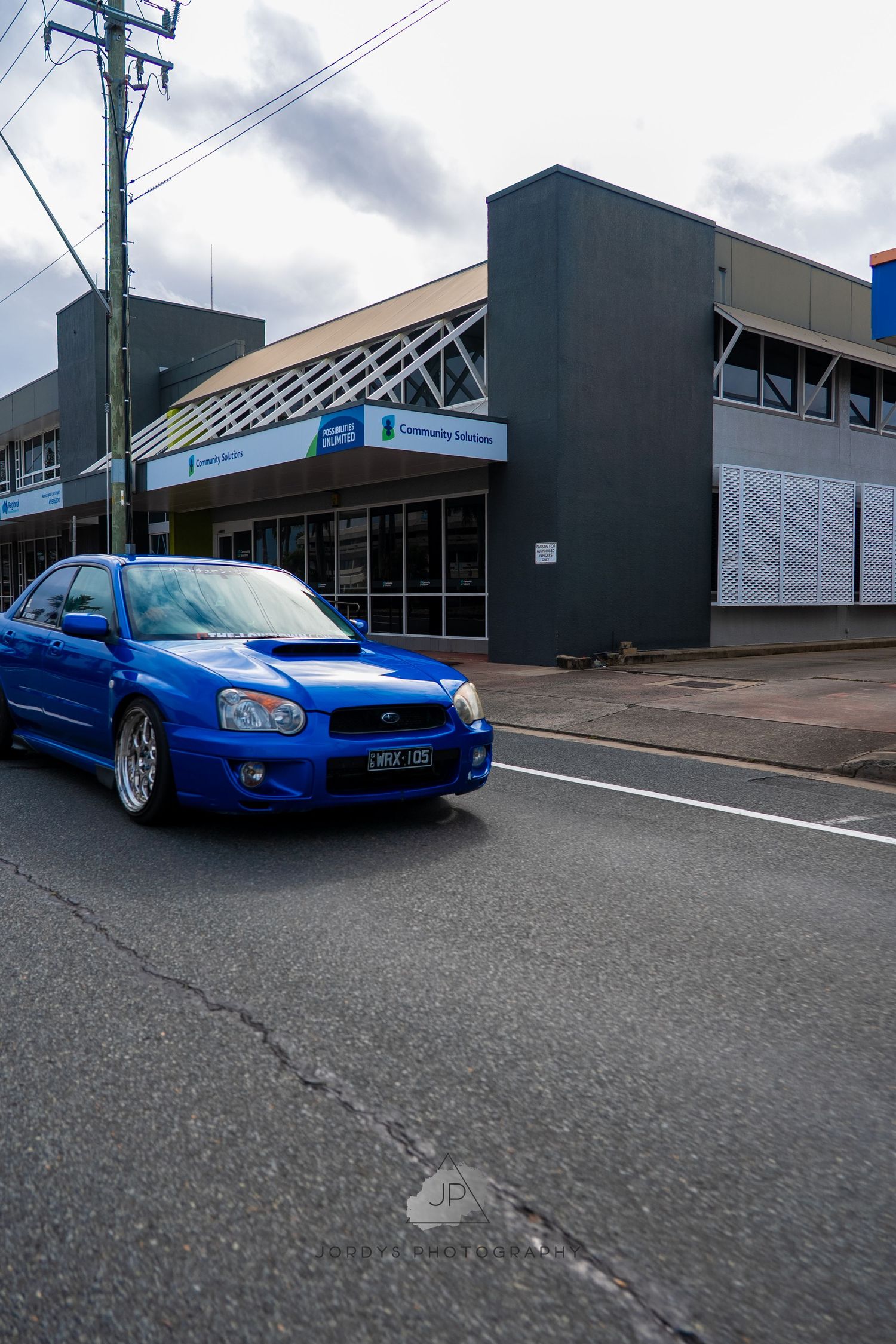 A modified blue Subaru WRX with lowered suspension and aftermarket wheels shown from multiple angles in a parking lot.