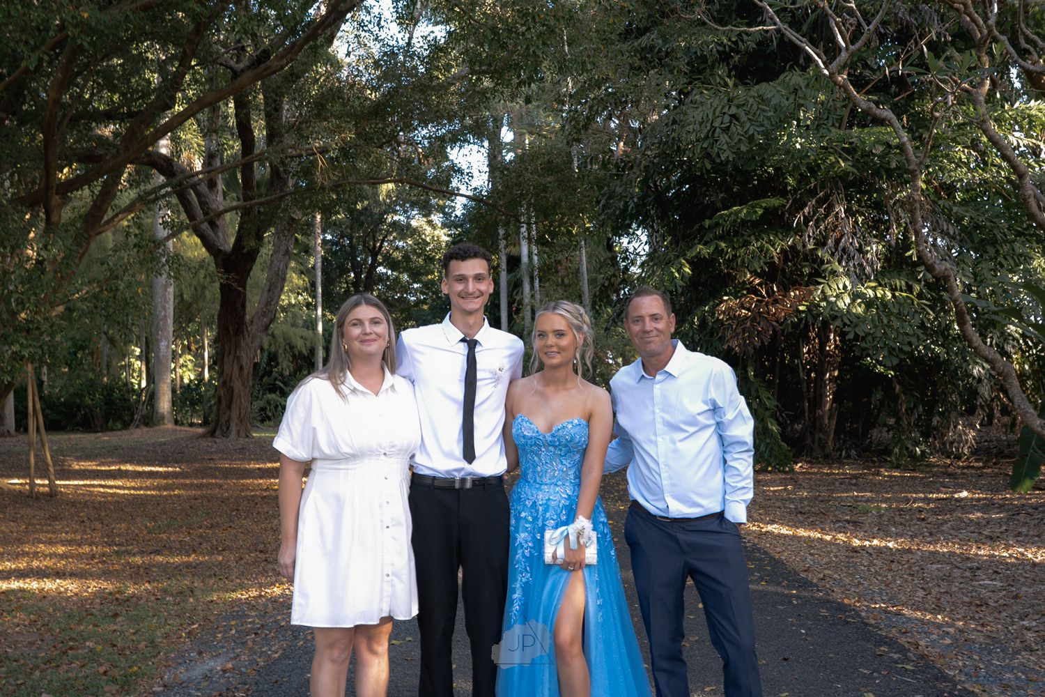Group of people walking together on a tree-lined path during an outdoor gathering.