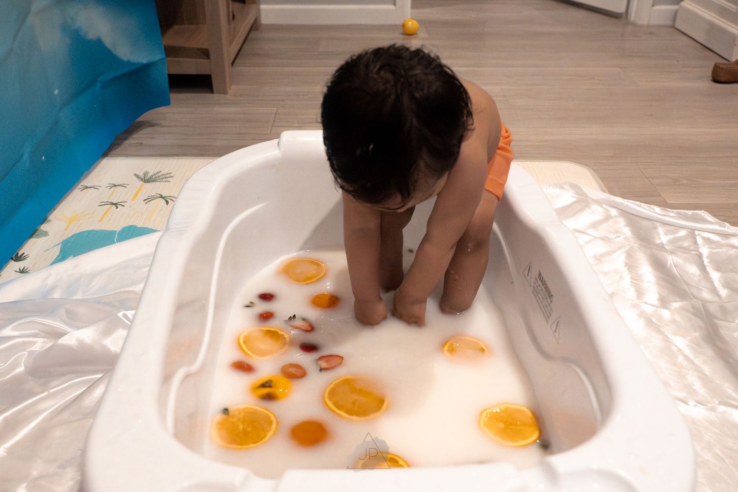 A small cat playfully bats at orange goldfish stickers placed on a white surface.