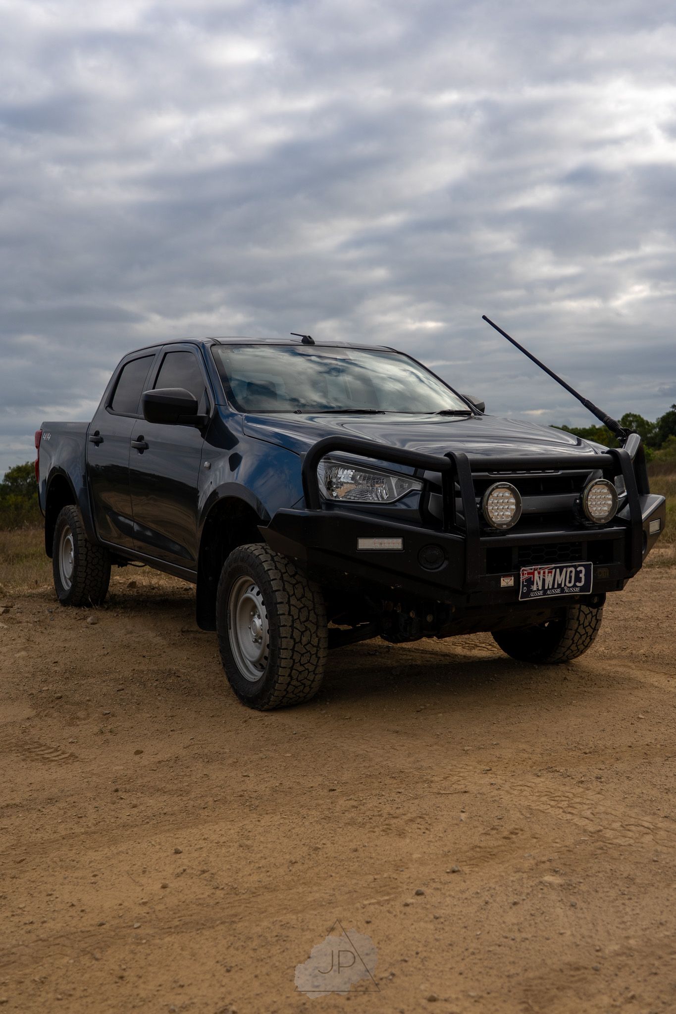 Black custom off-road racing car shown from different angles parked on dirt terrain under cloudy skies.