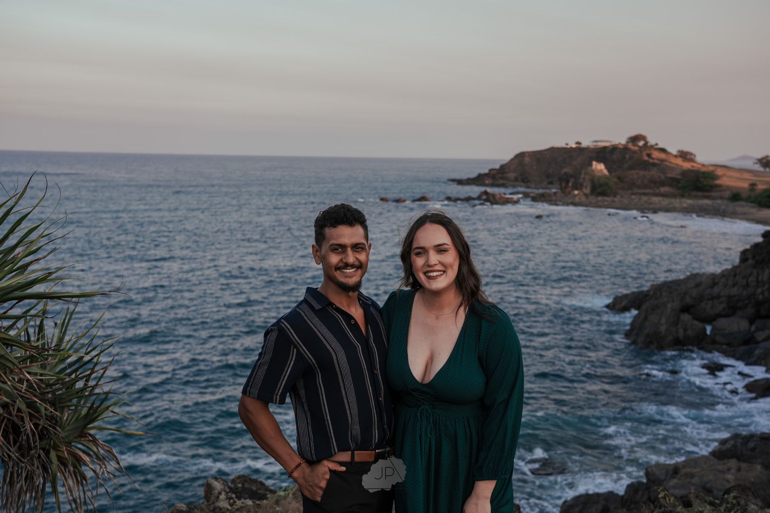 Couple enjoying scenic coastal views along rocky ocean cliffs at sunset.