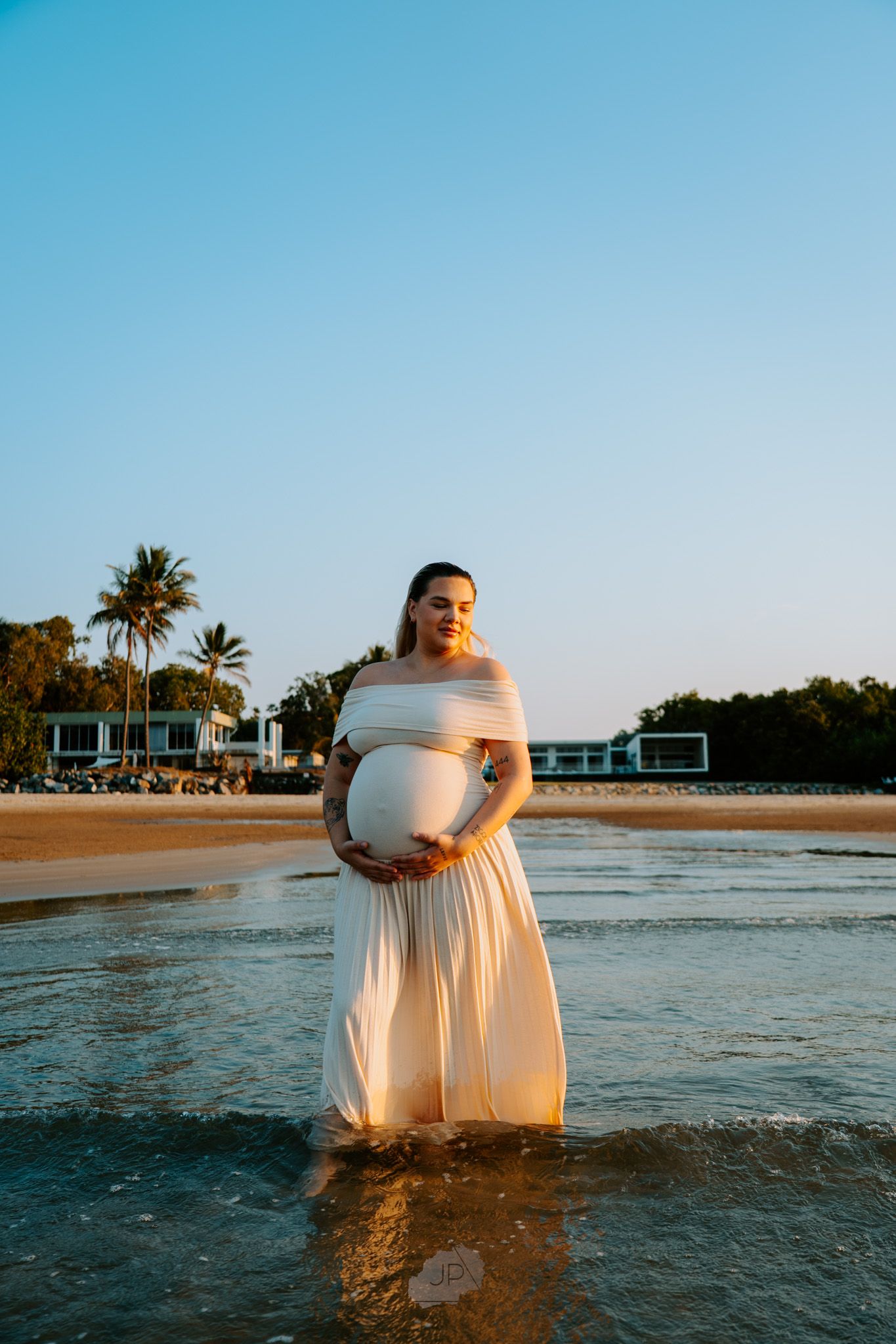 A series of photos showing a person in a white dress standing in shallow ocean water during sunset at a beach.